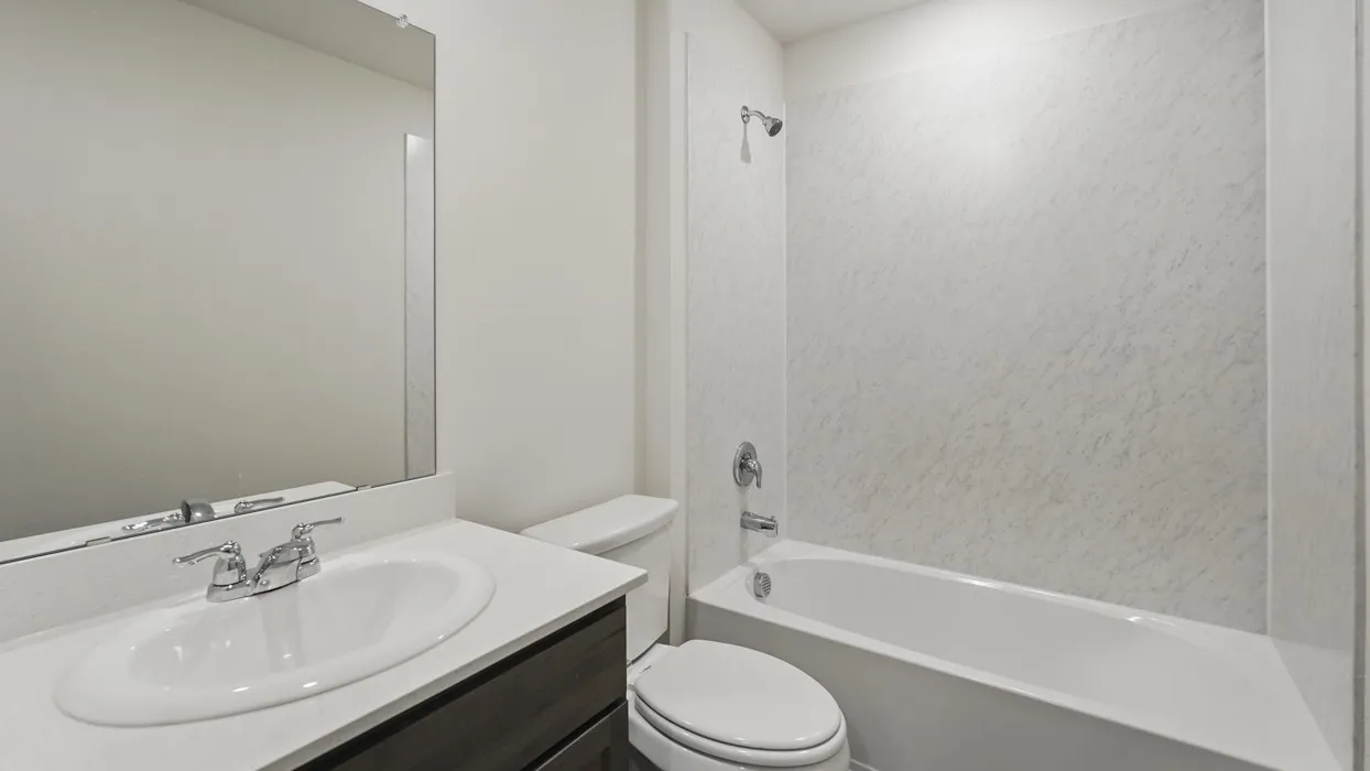 Bathroom featuring a white bathtub, shower with white surround, polished chrome fixtures, dark wood-finish vanity, white countertop, and integrated sink