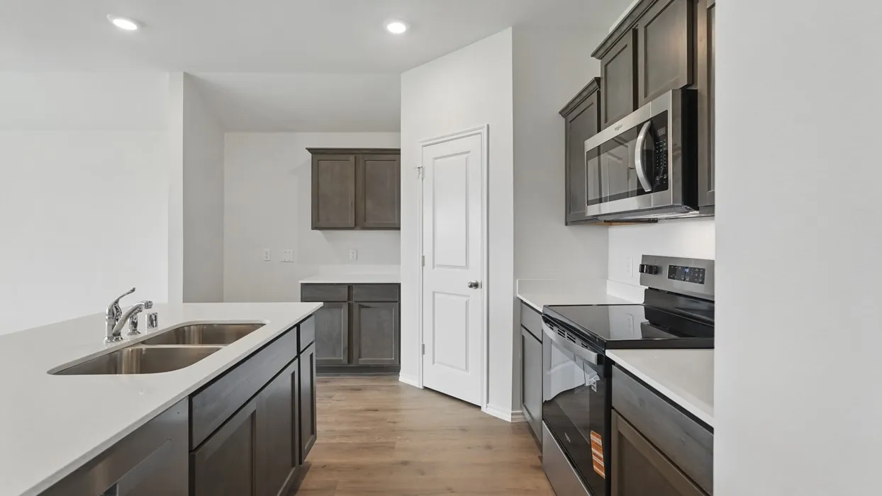 Kitchen featuring dark wood-finish cabinetry, light countertops, stainless steel appliances, and wood-finish flooring