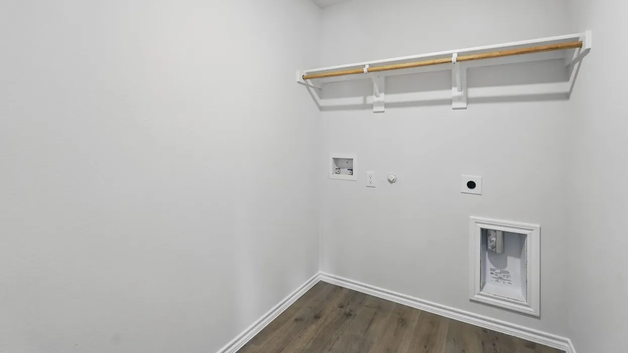 Laundry area with wood-finish flooring, white baseboards, and light-toned walls