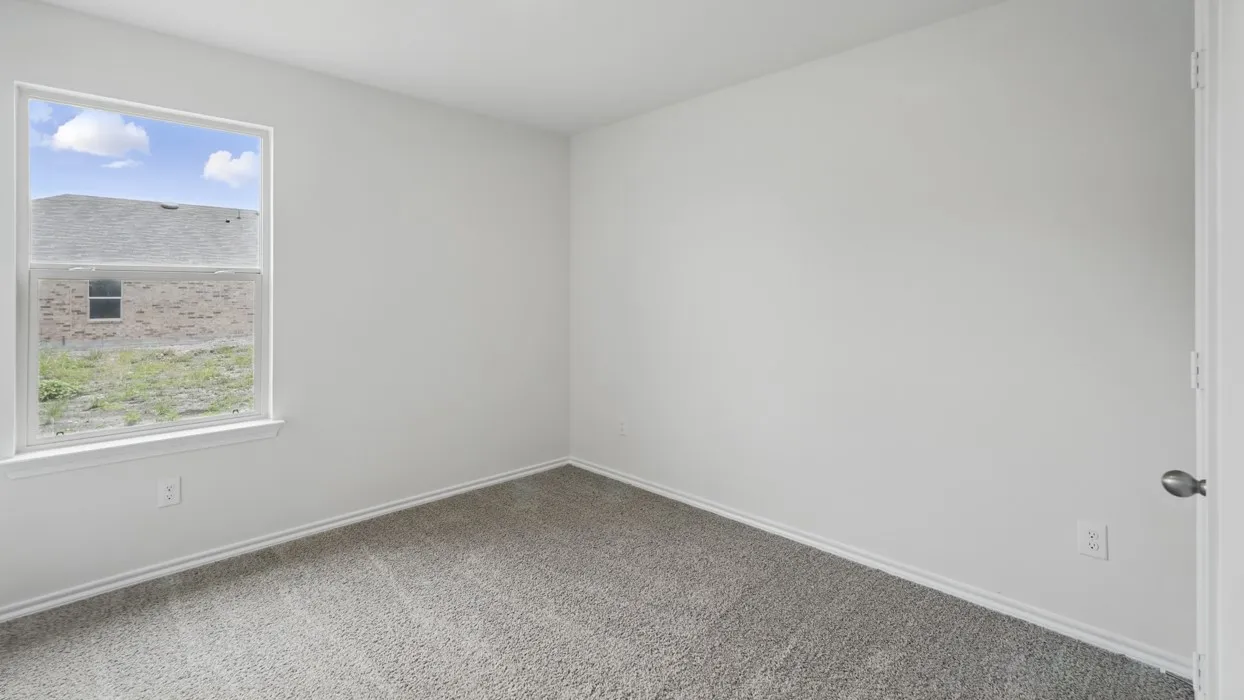Neutral tone interior featuring a white painted wall, gray carpet flooring, and white baseboards