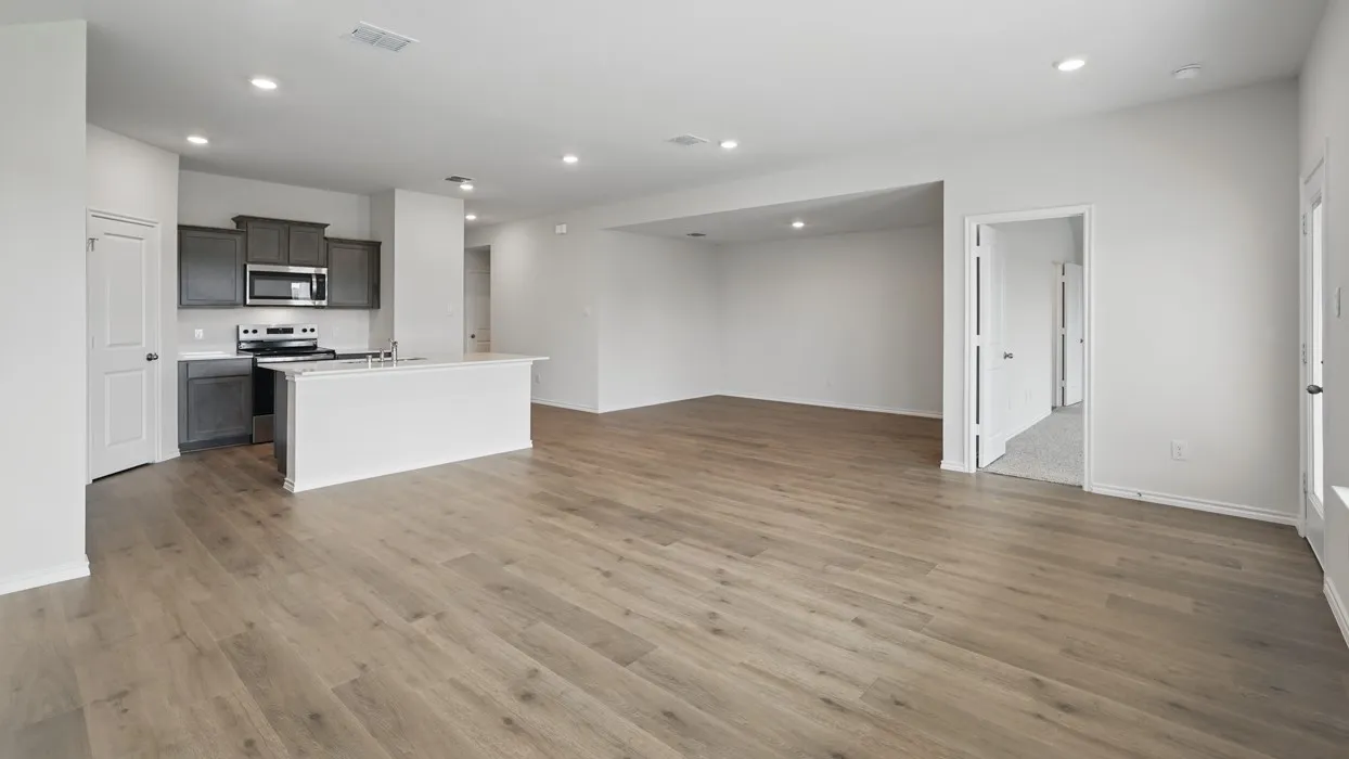 Expansive open-concept living area featuring wood-finish flooring, recessed lighting, and a kitchen with dark cabinetry