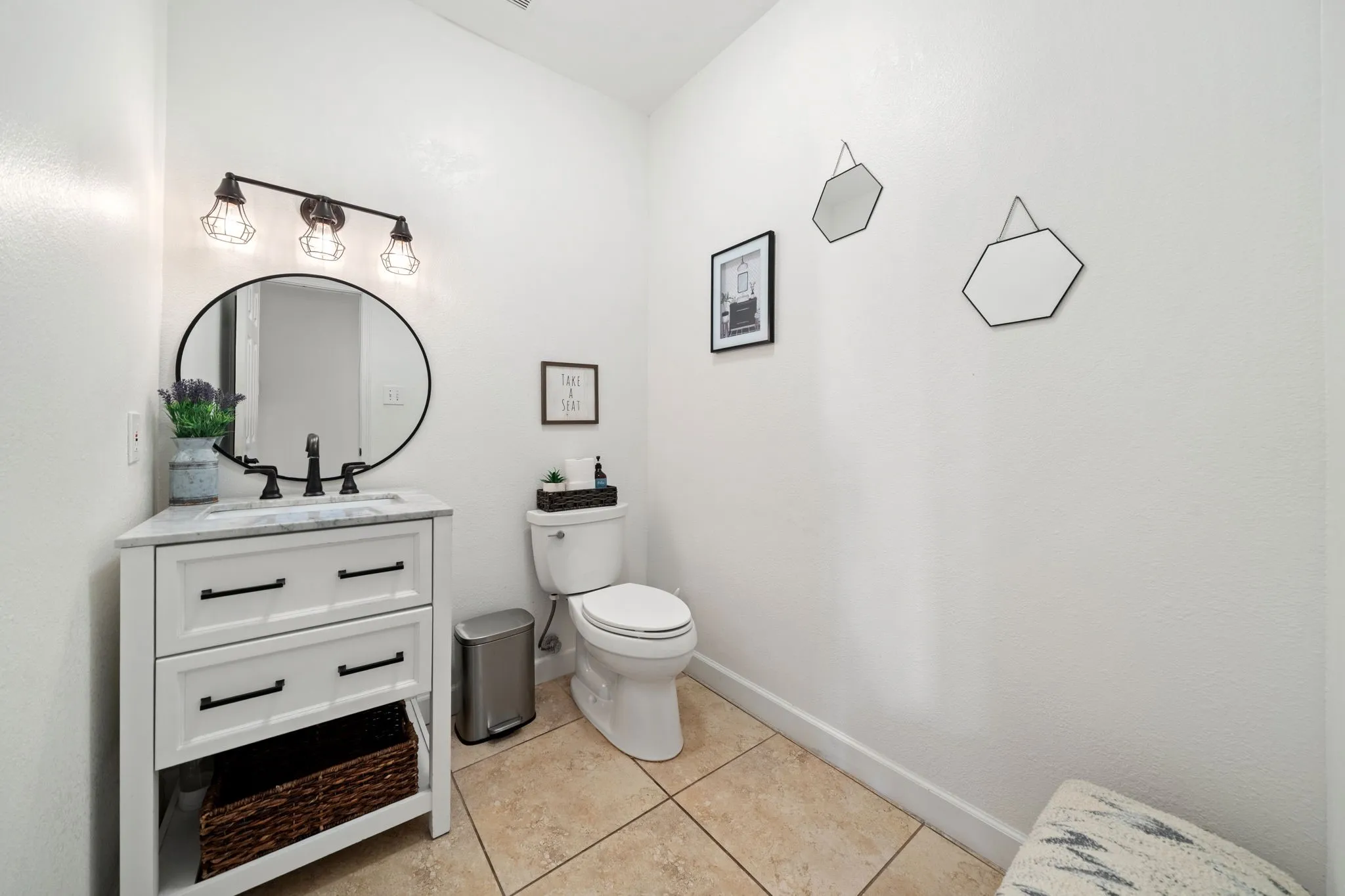 White vanity with a rectangular sink, dark faucet, and an oval-framed mirror