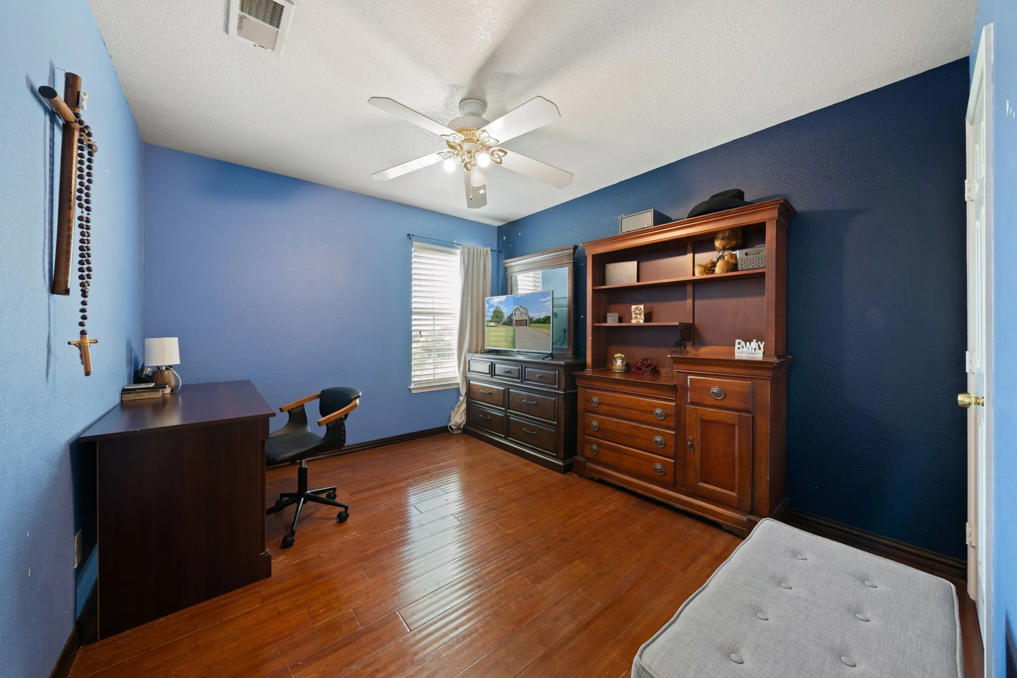 Interior room featuring wood-finish flooring, a ceiling fan with integrated lighting, and window blinds for natural light control