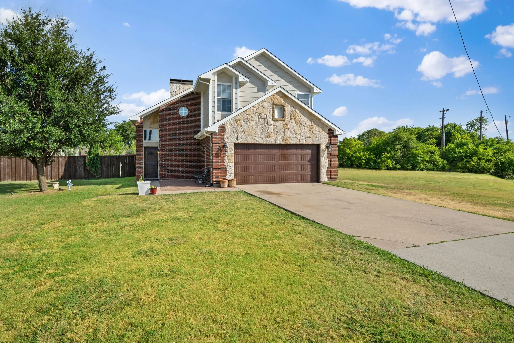Two-story residence featuring a brick and stone facade, an attached two-car garage with a brown door, and a concrete driveway