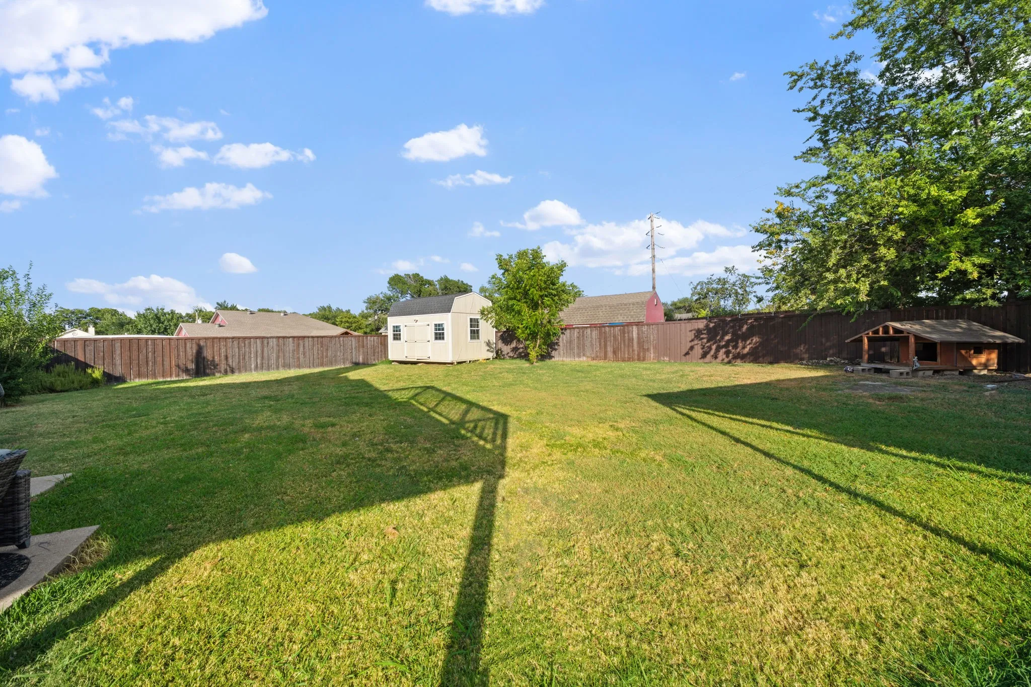 Expansive backyard with a manicured lawn, a detached storage shed, mature trees, and privacy fencing