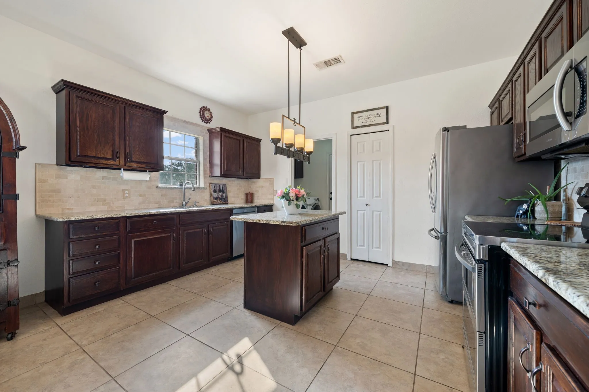 Kitchen featuring dark wood cabinetry, light-toned tile flooring, and light granite countertops