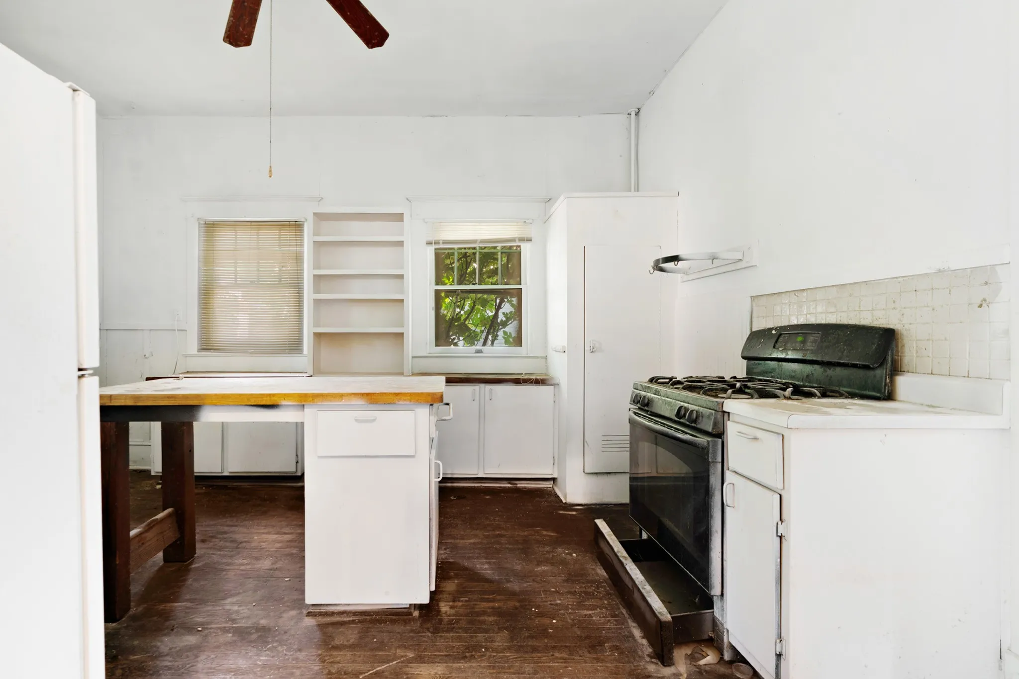 Kitchen space featuring a gas range, tile backsplash, built-in cabinetry, and a ceiling fan