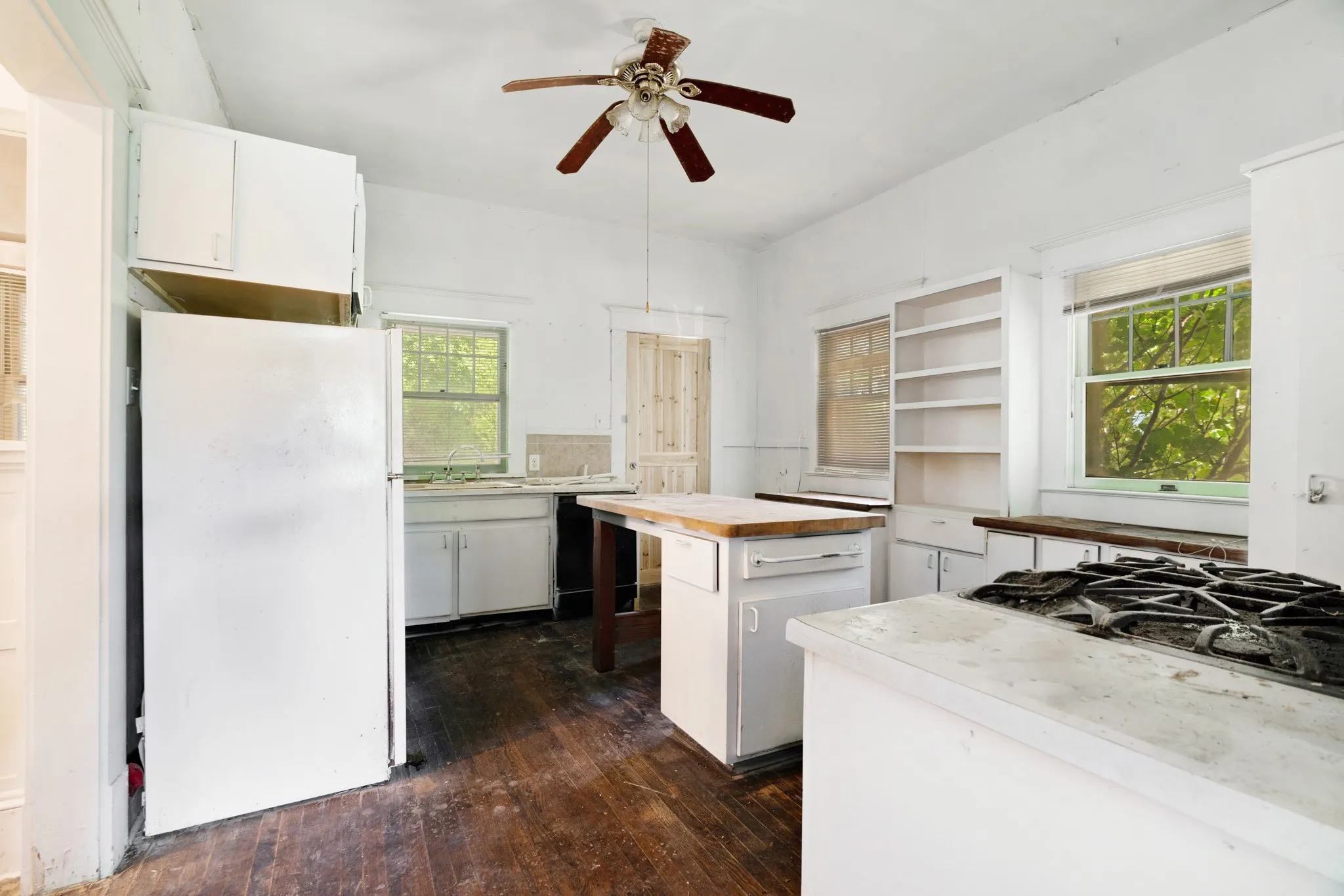 Kitchen featuring wood-finish flooring, white cabinetry, a built-in gas range, and multiple windows