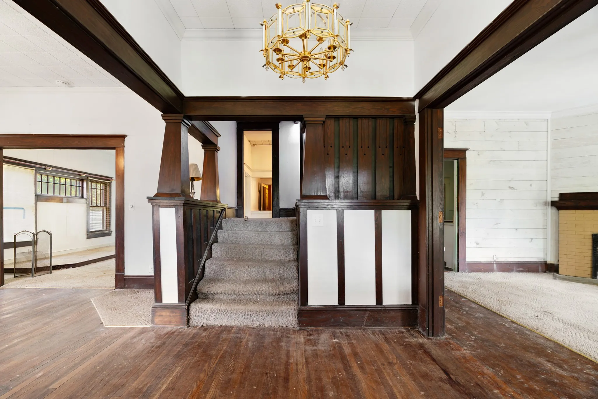 Grand entryway featuring wood-finish flooring and a central staircase with carpeted treads