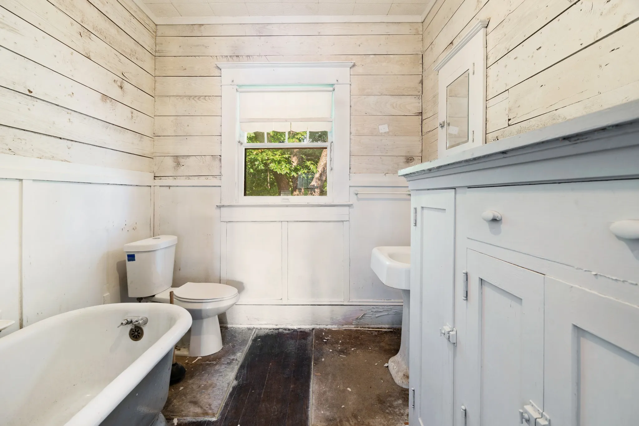 Bathroom featuring a clawfoot tub, pedestal sink, and built-in white cabinetry