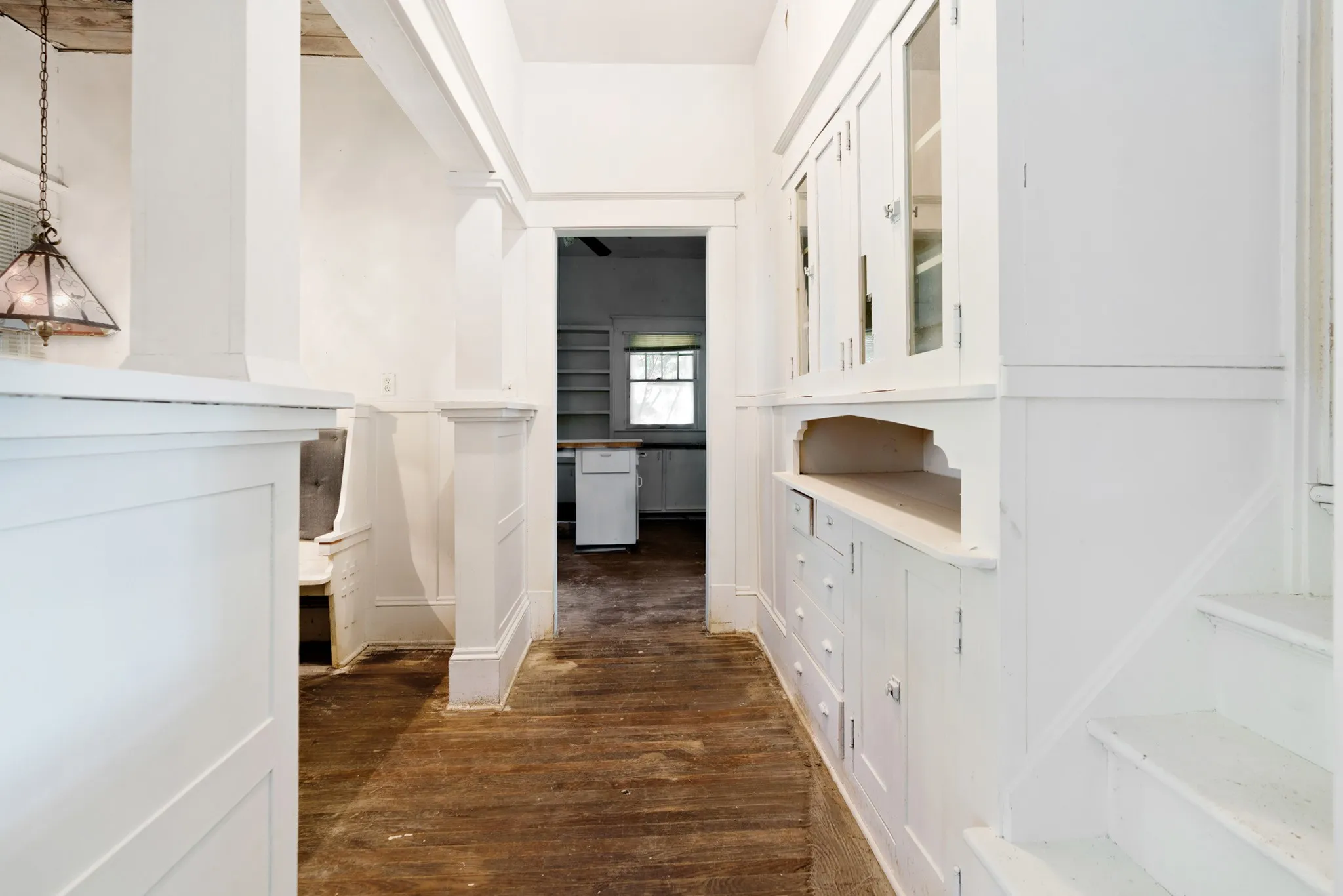 Hallway featuring built-in cabinetry with glass-front uppers and drawers, wood-finish flooring, white paneled walls, and a recessed ceiling