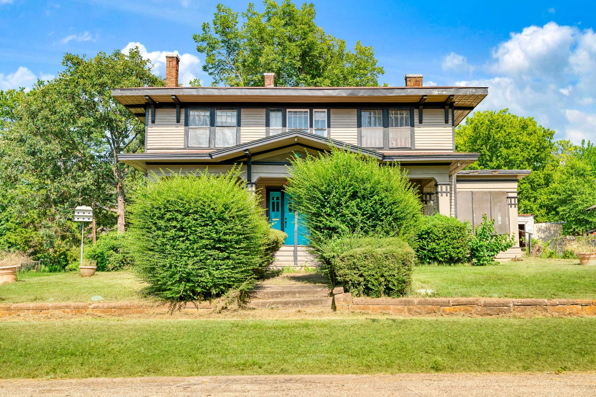 Craftsman-style facade featuring beige siding, dark trim accents, a vibrant blue front door, and a covered porch