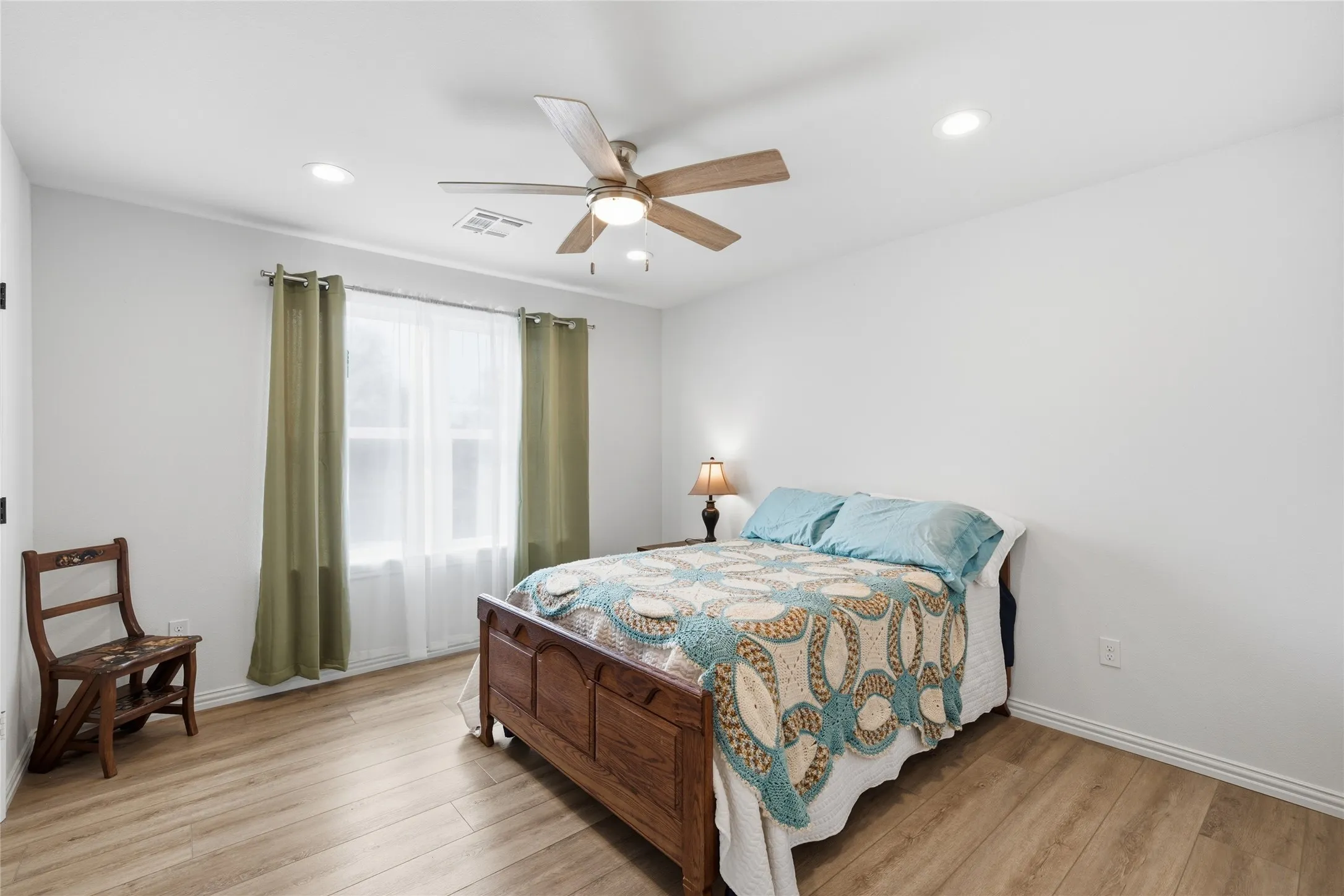 Bedroom featuring light wood-finish flooring, a ceiling fan with integrated lighting, recessed lighting, and a window with curtain rods