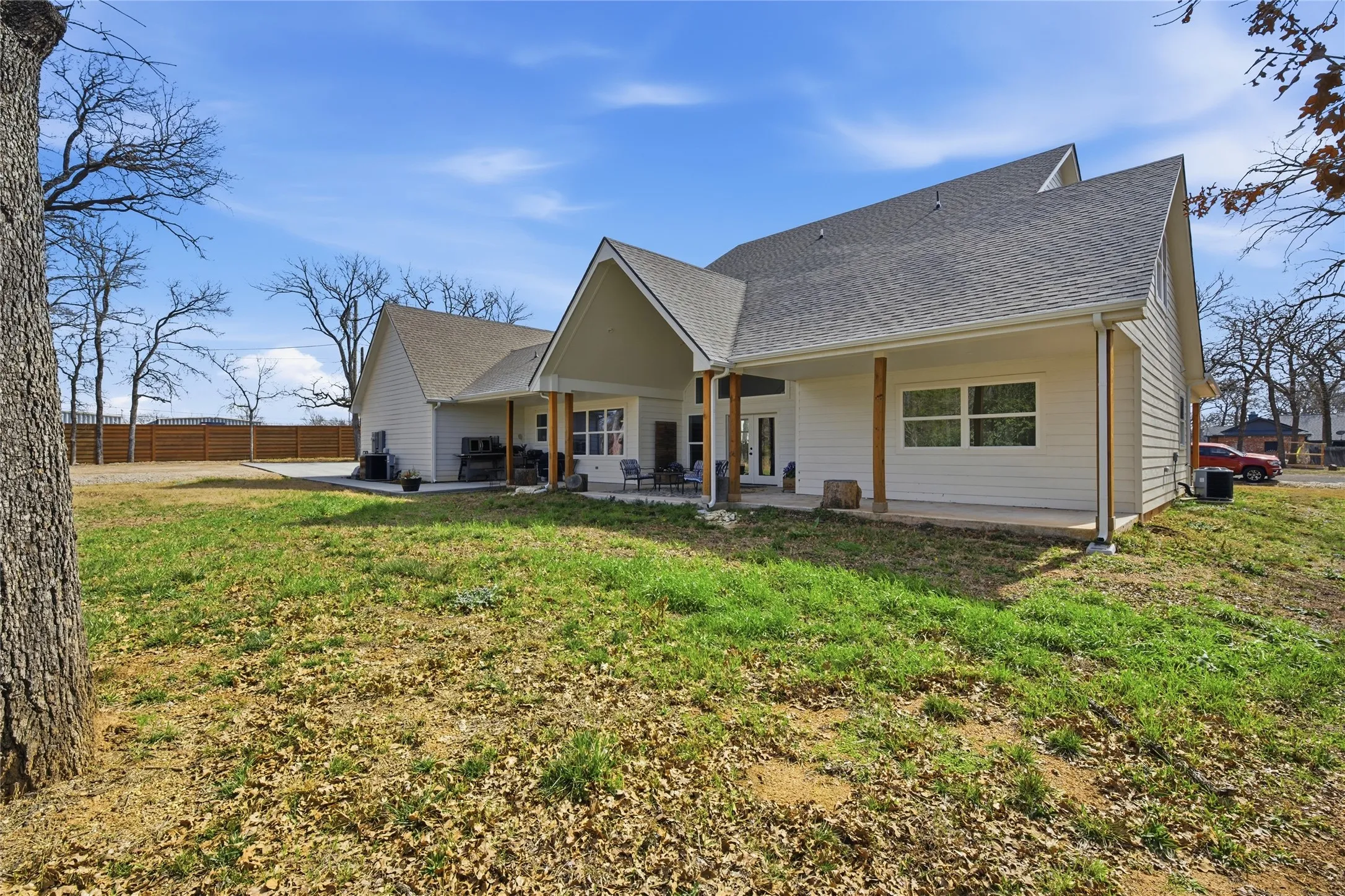 Rear exterior featuring white siding, a covered patio with wood columns, and a gabled roofline