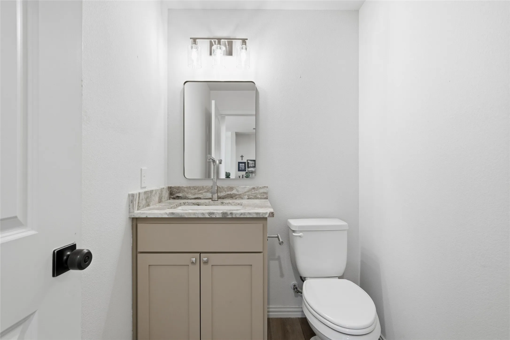 Powder room featuring a single vanity with a neutral-toned cabinet, a light-toned countertop, and an undermount sink