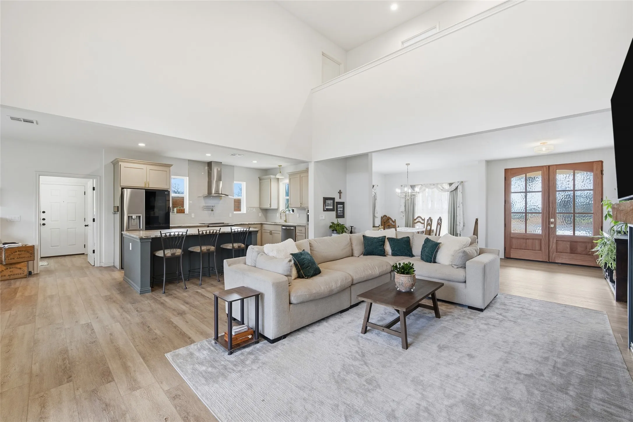 Bright living area featuring vaulted ceilings, wood-finish flooring, and a kitchen with an island breakfast bar