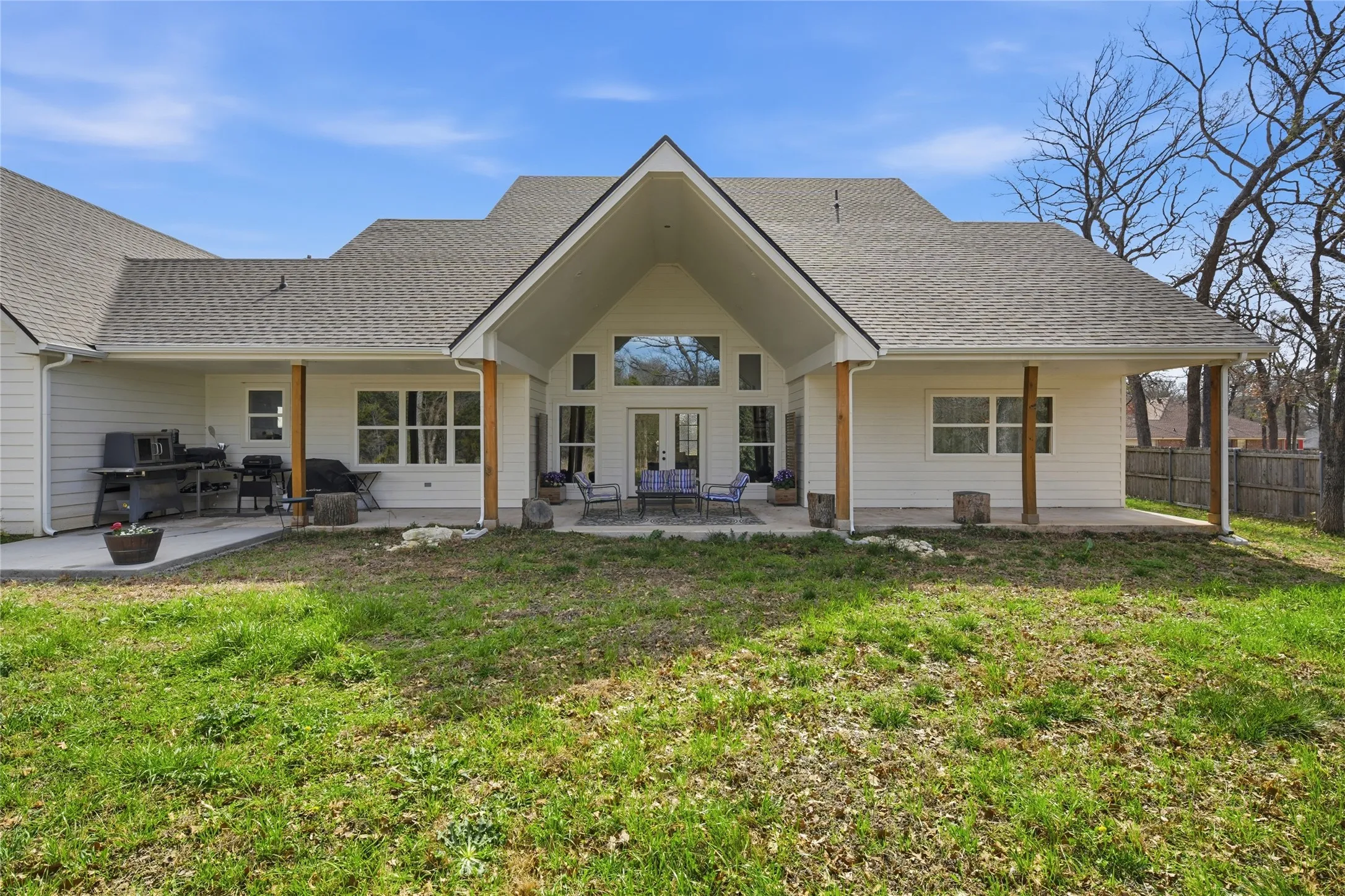Rear exterior featuring a large covered patio with wood support beams, multiple windows providing natural light, and a prominent peaked roofline