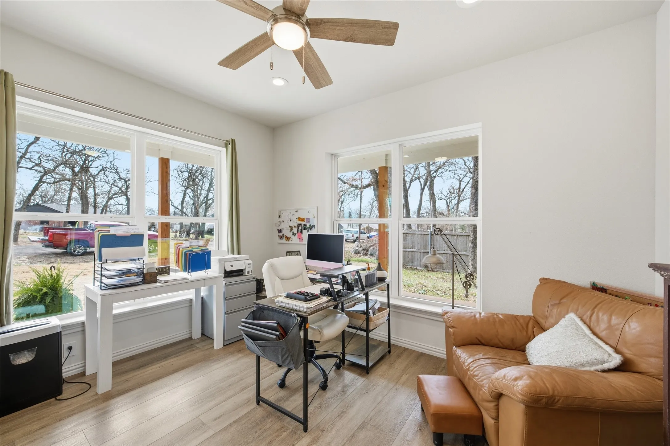 Bright room with wood-finish flooring and a ceiling fan