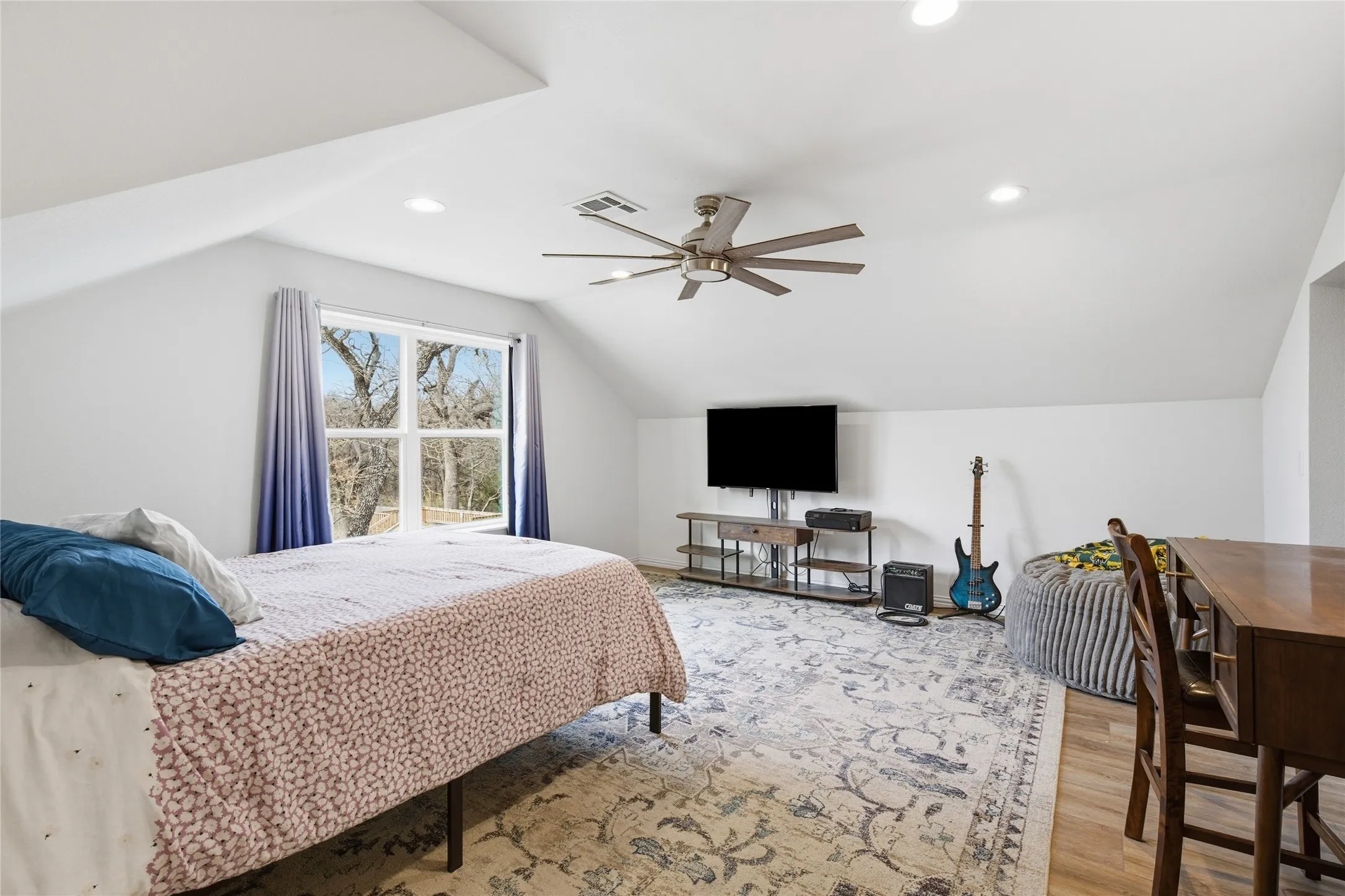 Spacious room featuring sloped ceilings, recessed lighting, and a modern ceiling fan