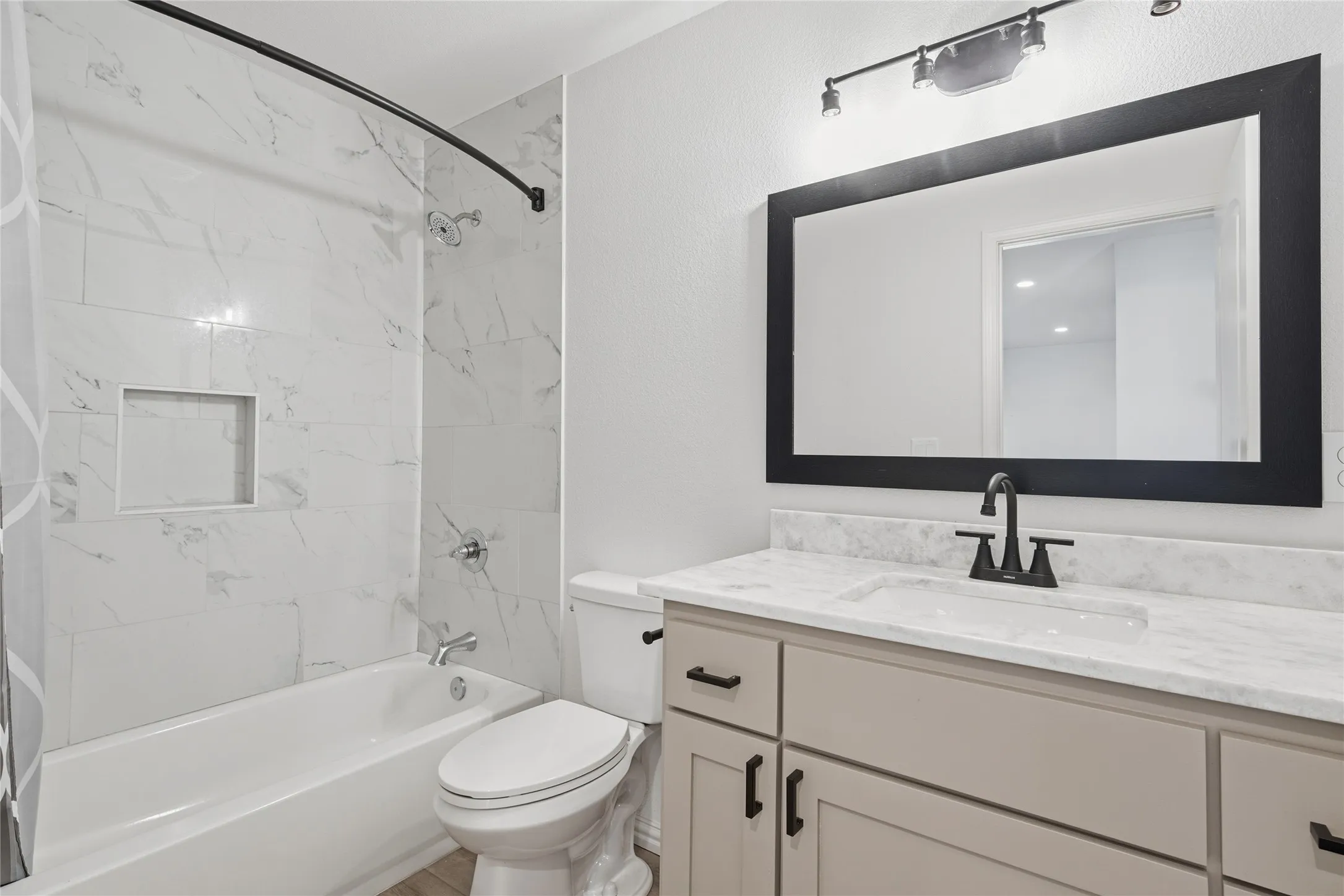 Bathroom featuring a white subway tile tub surround with built-in niche, a curved shower rod, and a white soaking tub