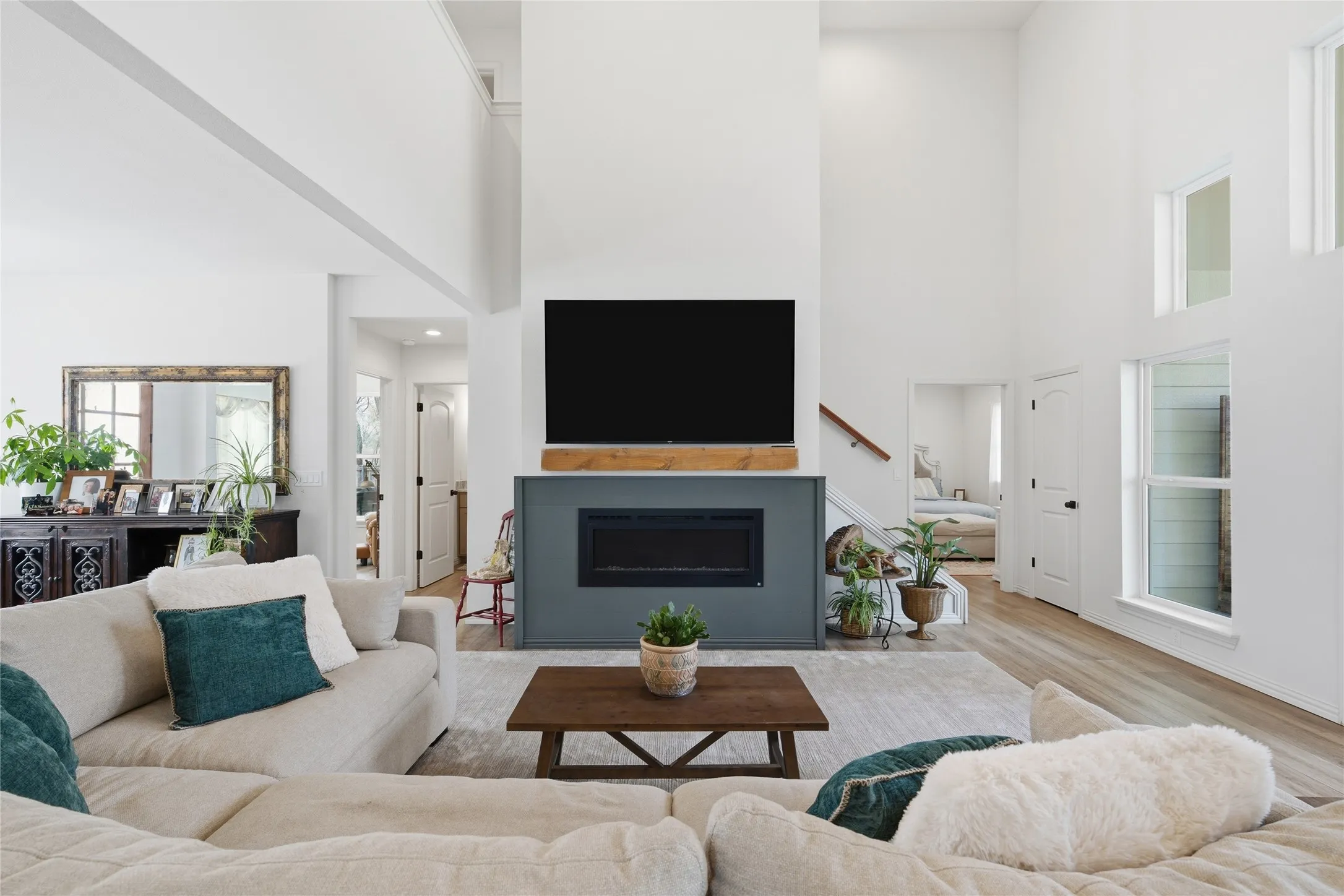 Spacious living area featuring a two-story ceiling, multiple large windows, and wood-finish flooring
