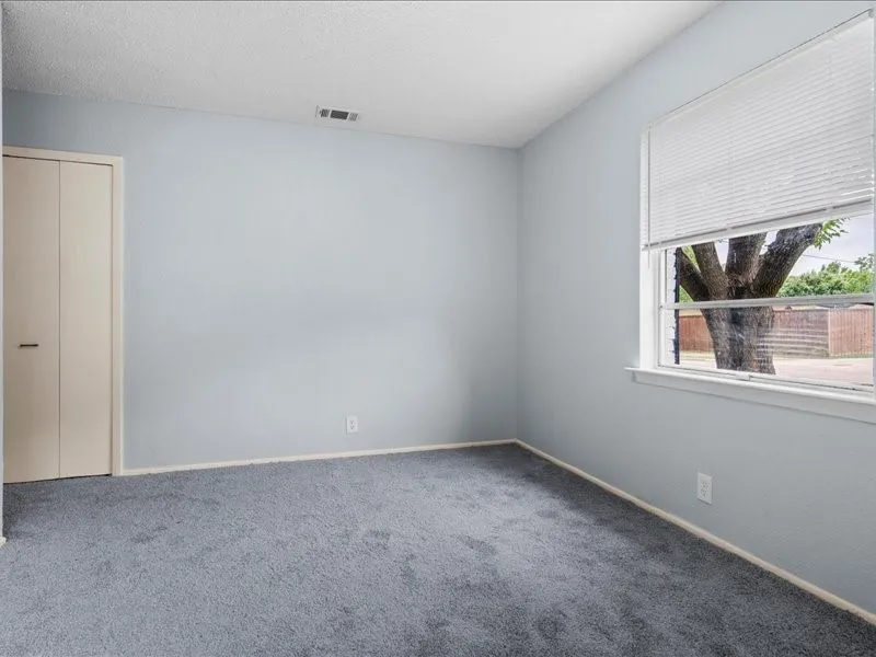 Neutral tone walls with a textured ceiling and gray carpet flooring
