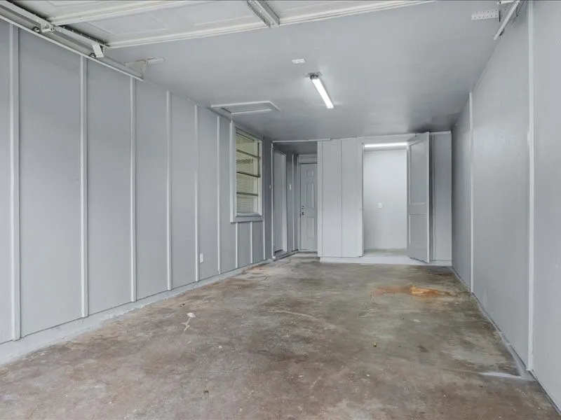Spacious garage featuring a concrete floor, painted paneling, and an exposed overhead door track