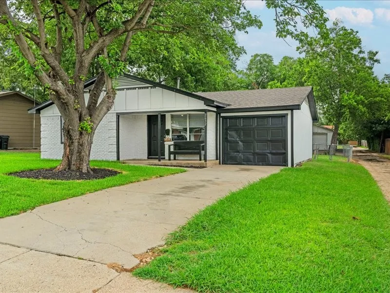 White exterior with black trim, featuring a single-car garage with a panel door