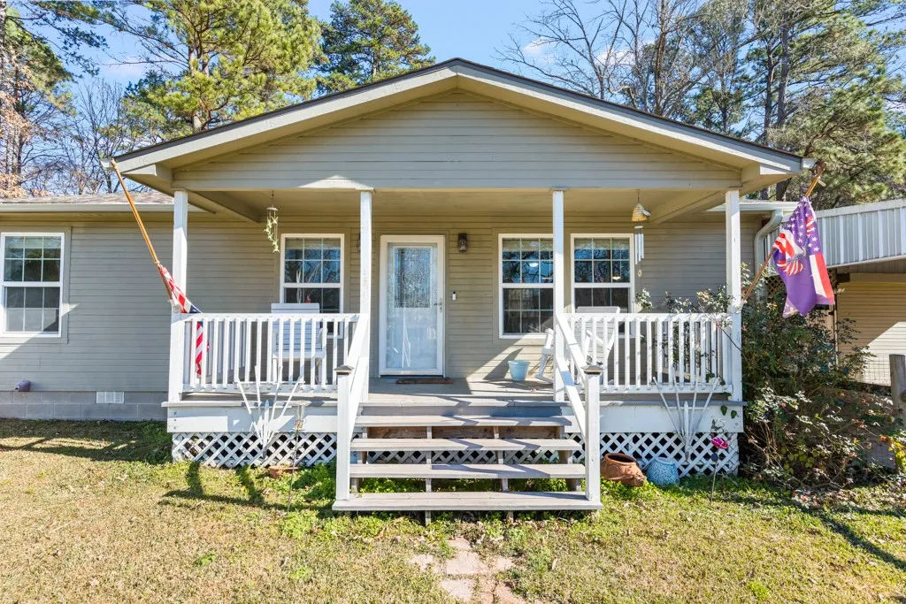 Front exterior featuring a covered porch, light-toned siding, and a partial lattice foundation skirt