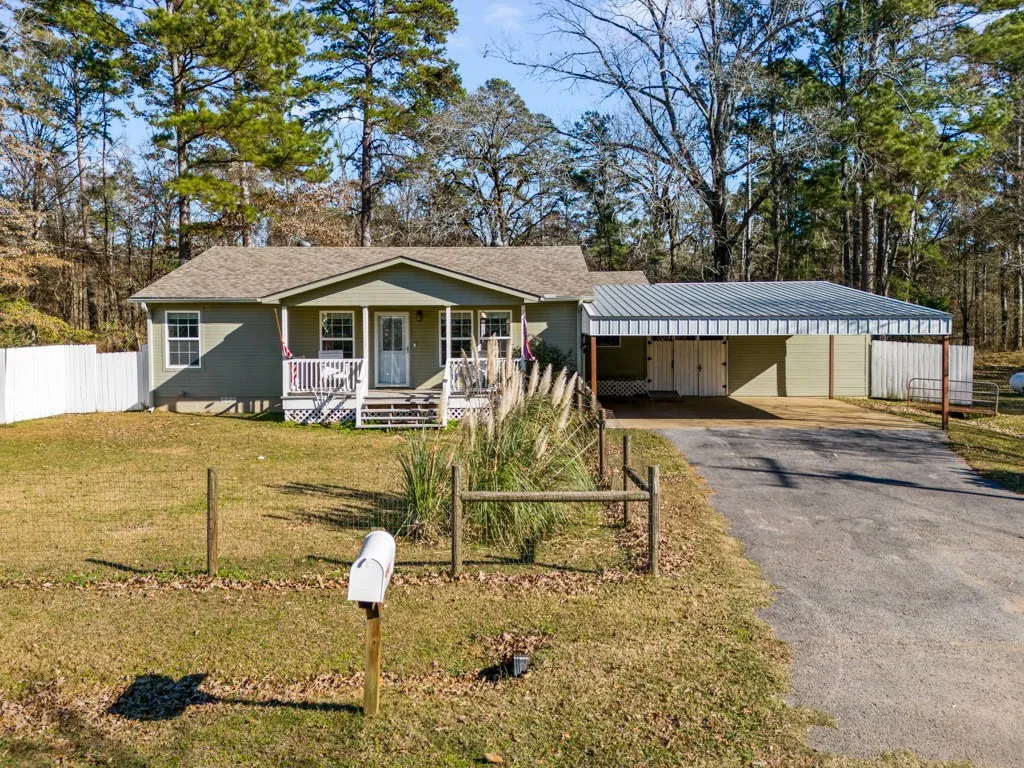 Ranch-style residence featuring a covered front porch, an attached carport, and an asphalt driveway