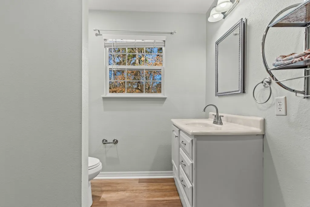 Bathroom featuring a single vanity with a white countertop and integrated sink, chrome faucet, and a wall-mounted mirror