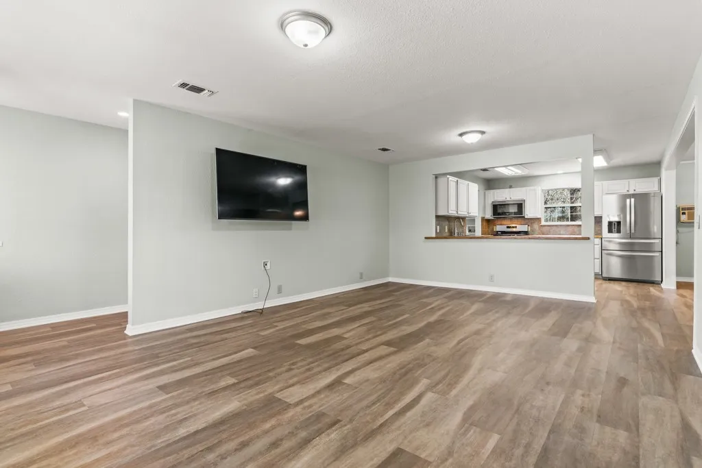 Open concept living area featuring wood-finish flooring, recessed lighting, and a partial wall opening to the kitchen
