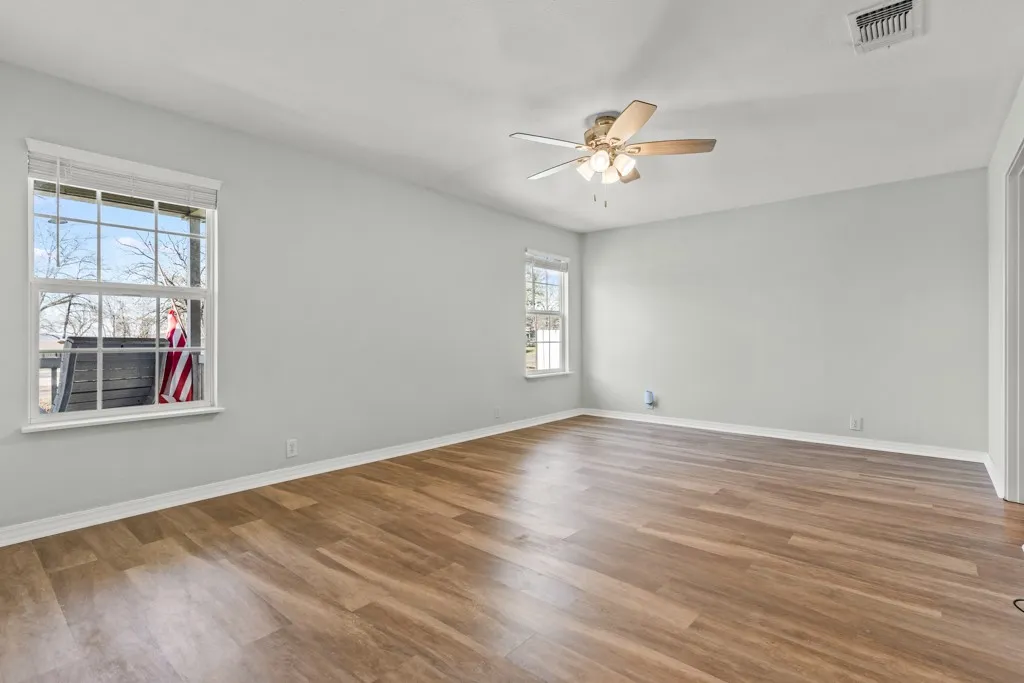 Spacious room featuring wood-finish flooring, light gray wall paint, and white baseboards
