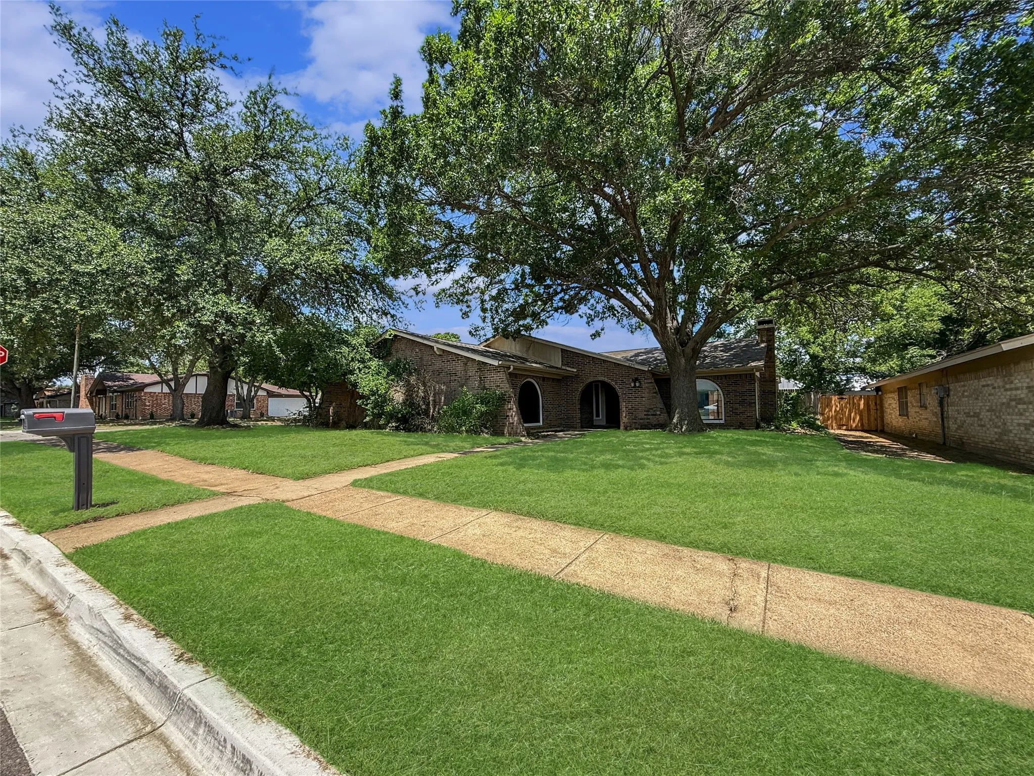 Brick exterior with arched entryways, a prominent chimney, and a mature tree providing natural shade