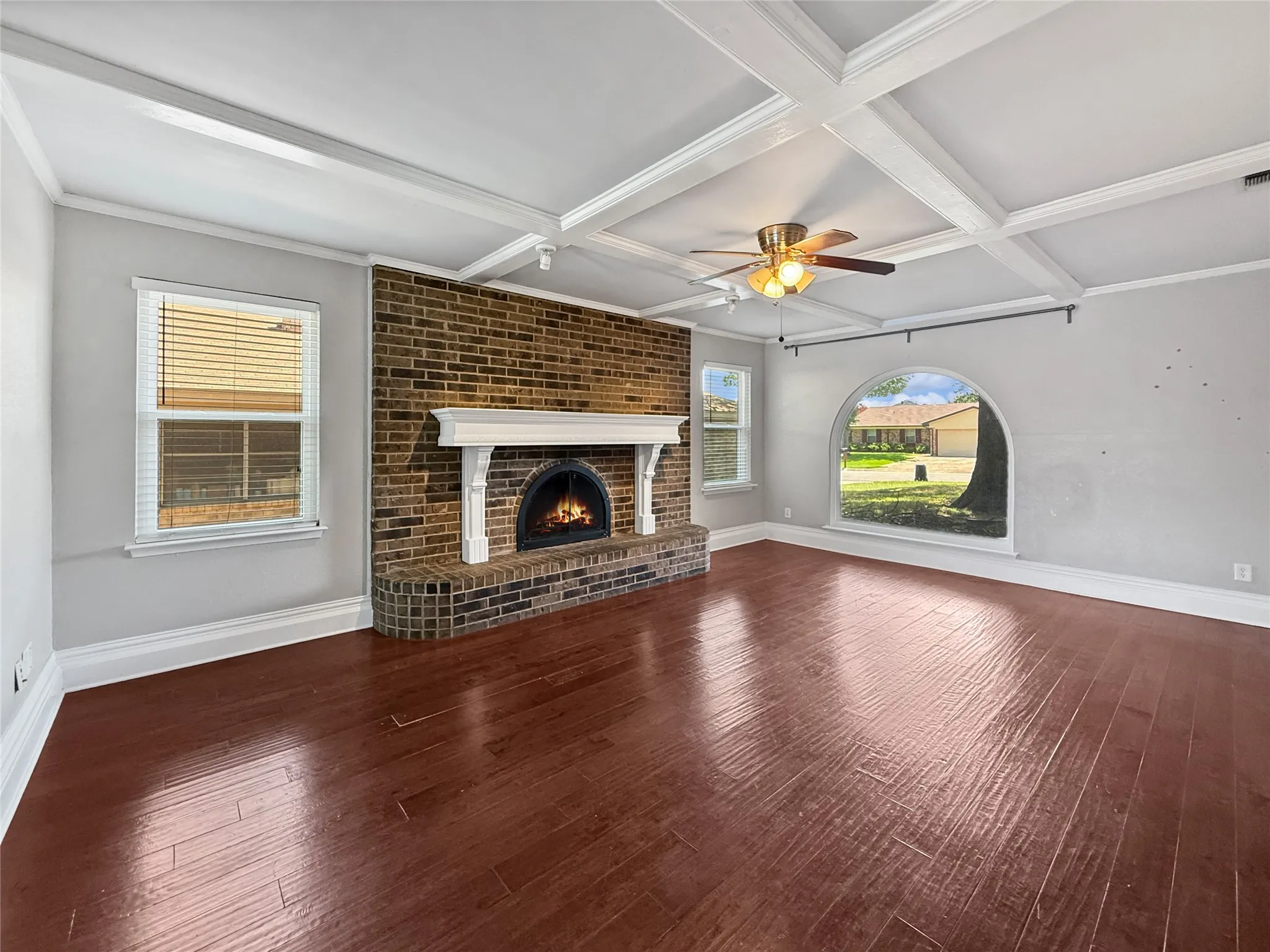 Spacious room featuring rich wood-finish flooring and a coffered ceiling