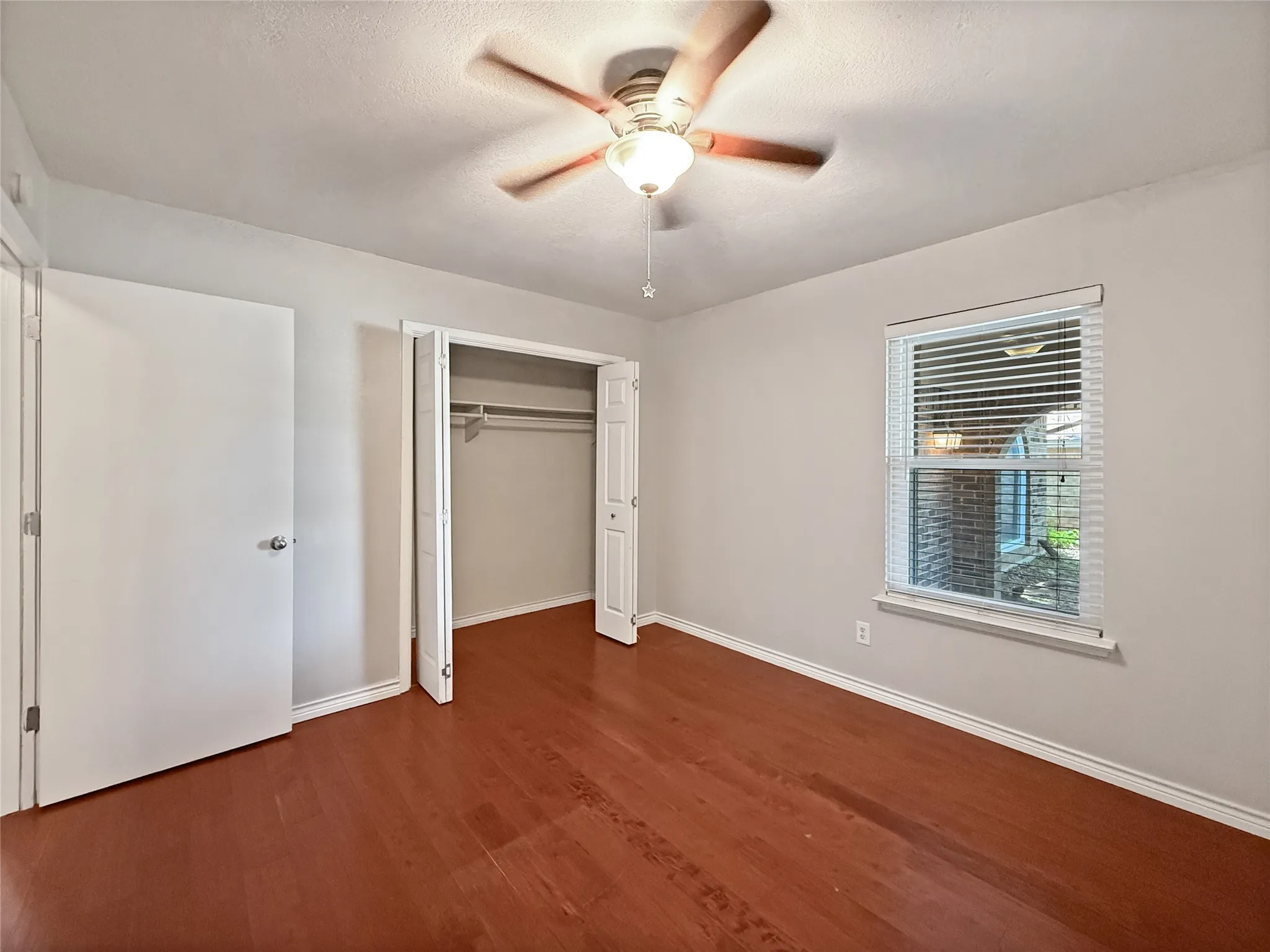 Room with wood-finish flooring, light gray walls, and white trim