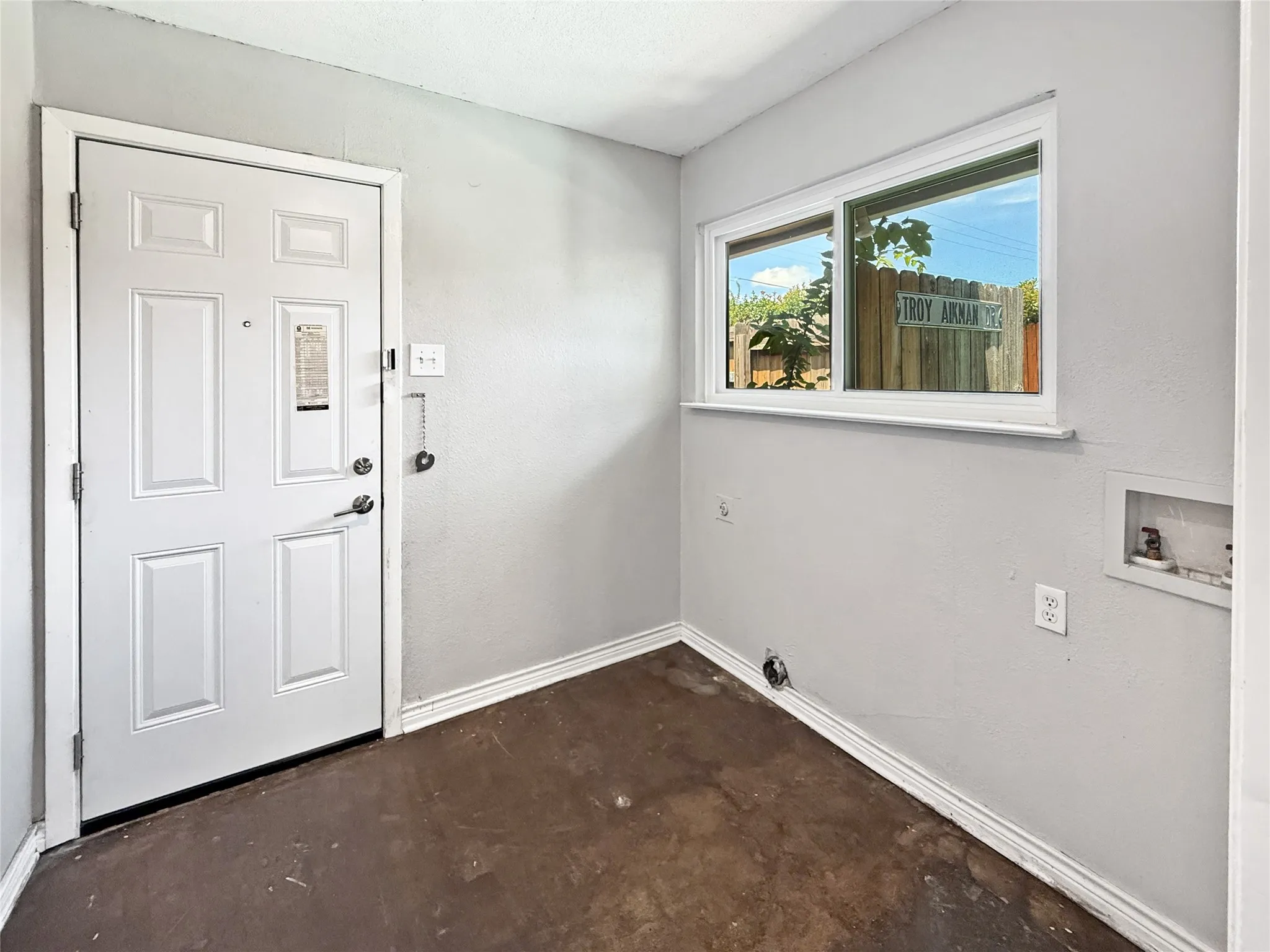 Utility room featuring a white panel door, light gray walls, white trim, and a horizontal window