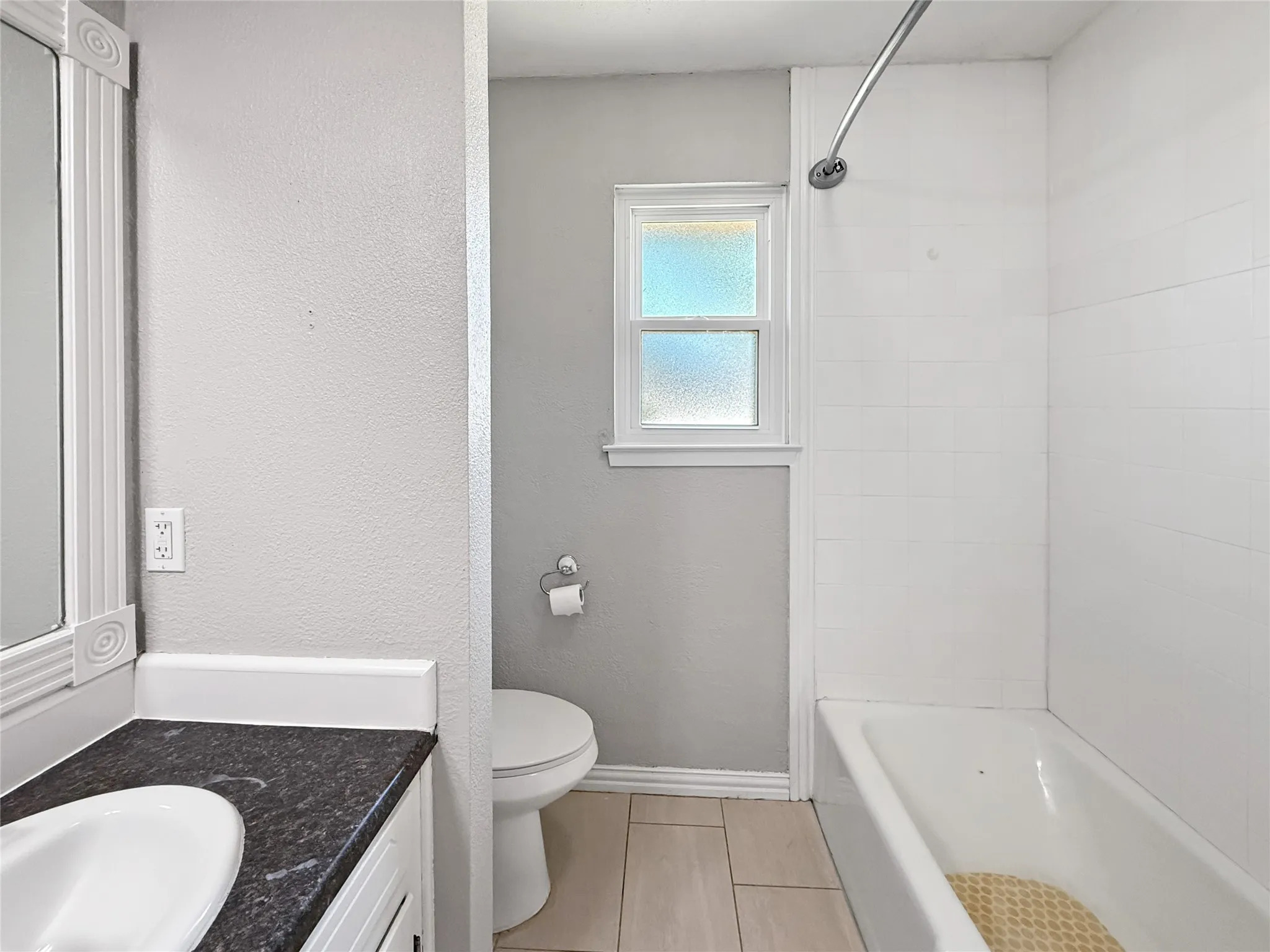 Bathroom featuring a white bathtub, white subway tile surround, and a frosted window