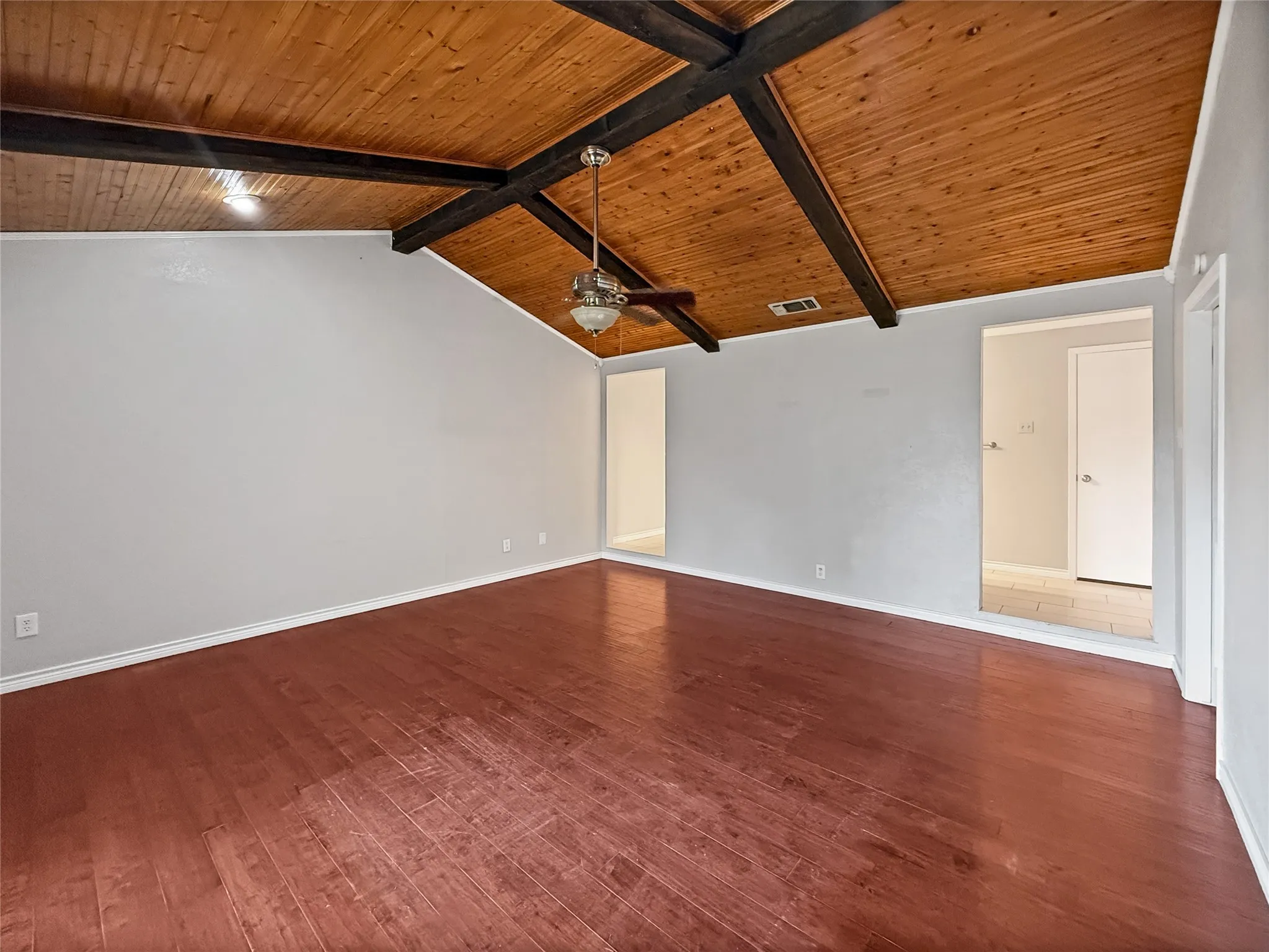 Vaulted wood-plank ceiling with exposed dark beams and a ceiling fan
