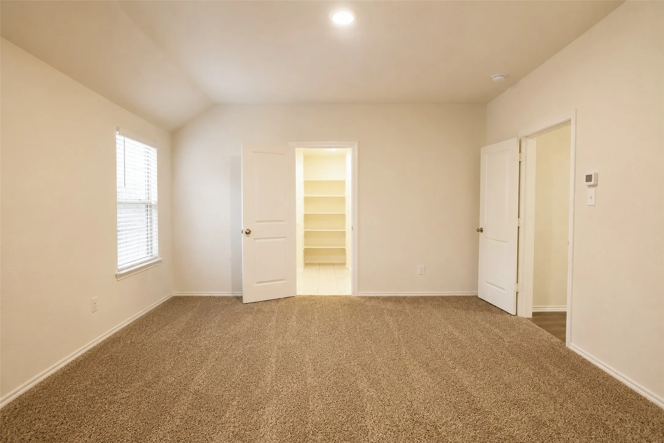 Carpeted room featuring a window with blinds, recessed lighting, and a closet with built-in shelving