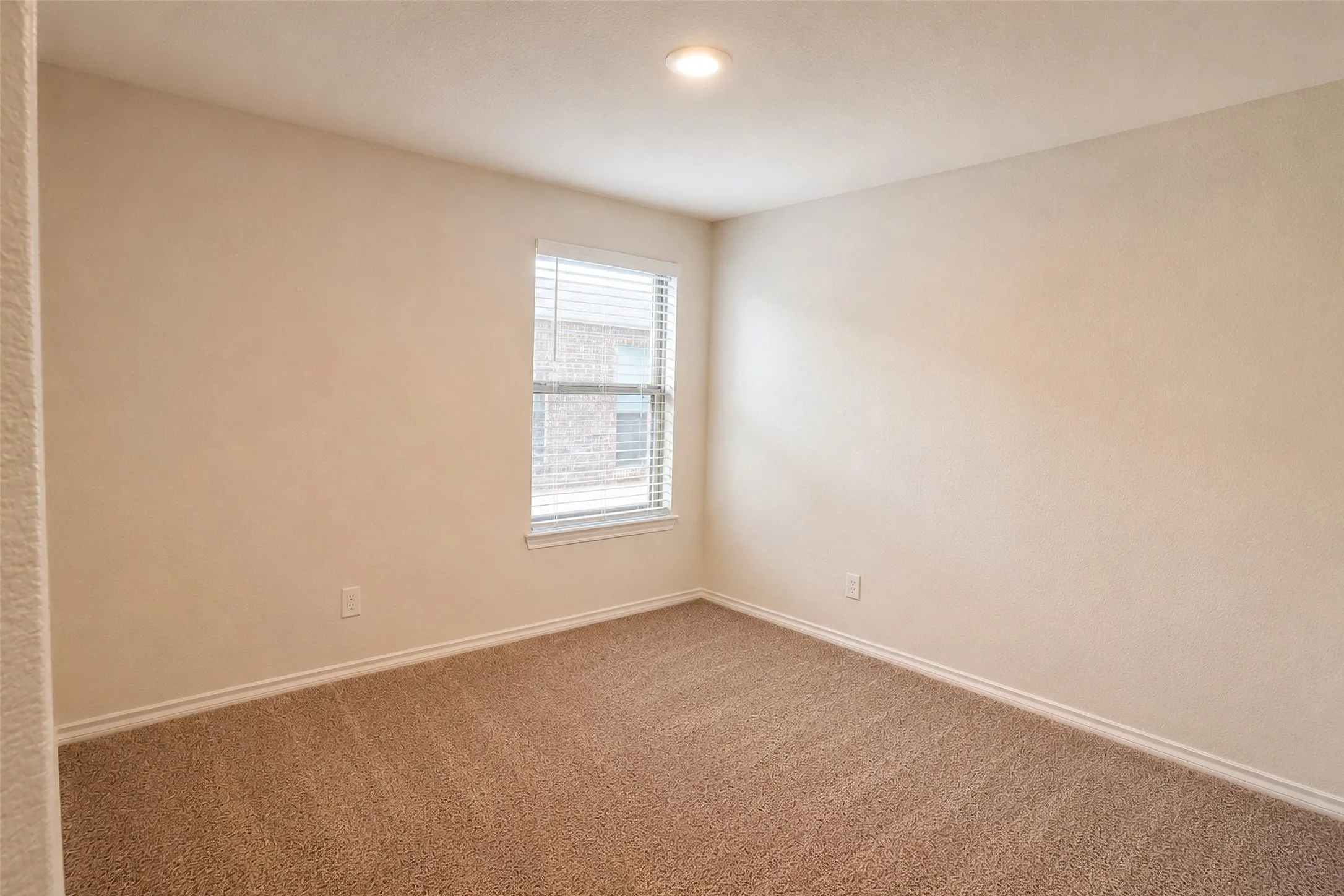 Carpeted room with a single window, recessed ceiling light, and neutral wall tones