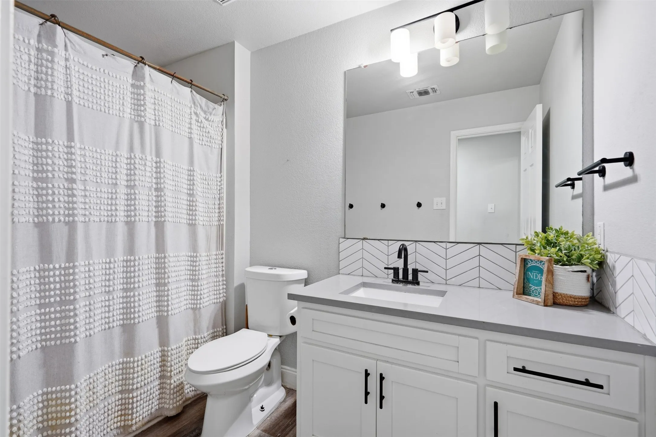Bathroom featuring a white vanity with black hardware, a rectangular undermount sink, and a gray countertop