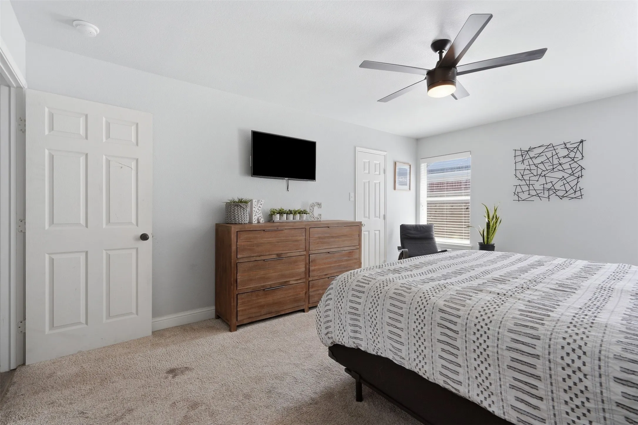 Carpeted room featuring a ceiling fan with integrated lighting, a panel door, and a window with horizontal blinds