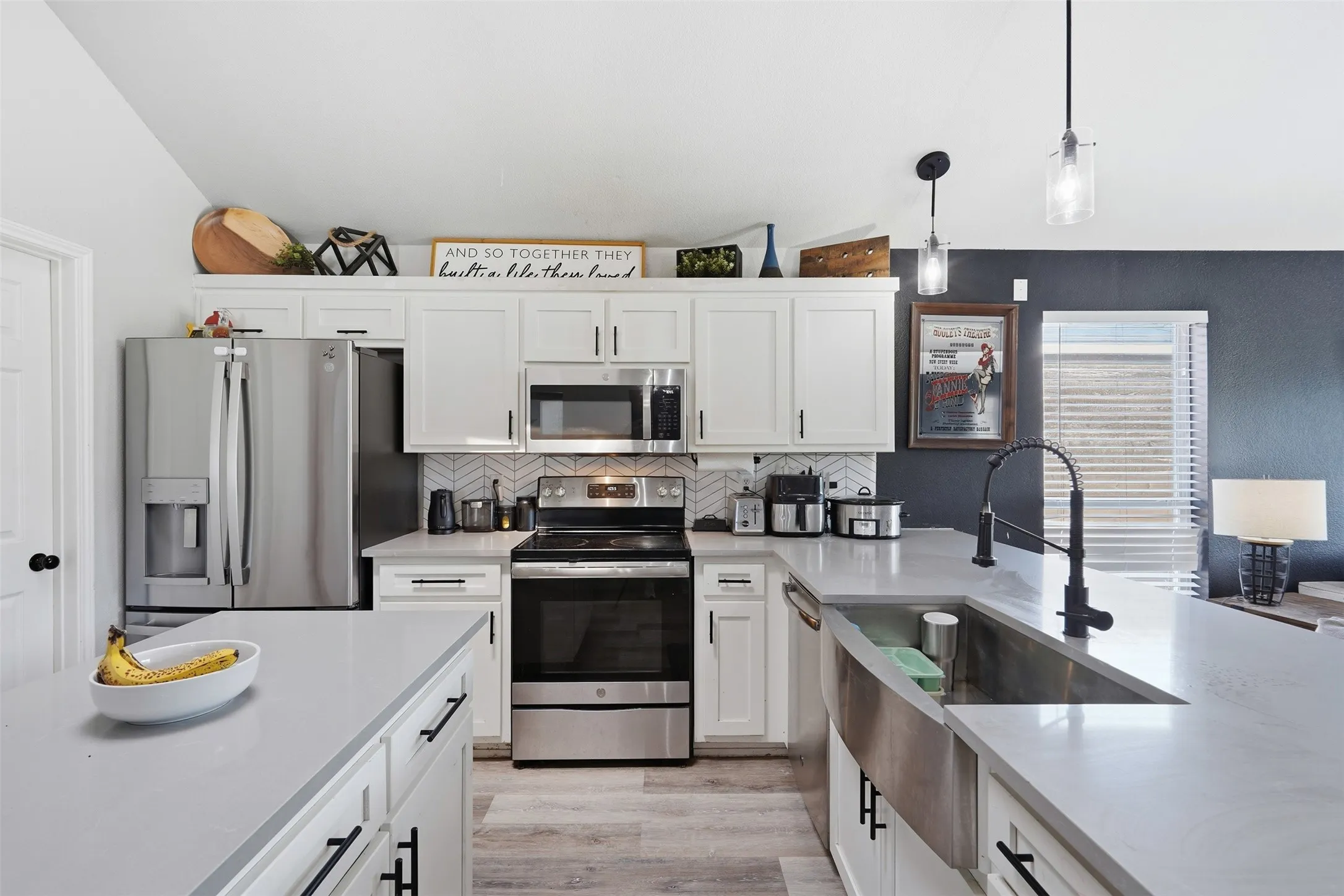 Kitchen featuring light-finish flooring and white cabinetry with black hardware
