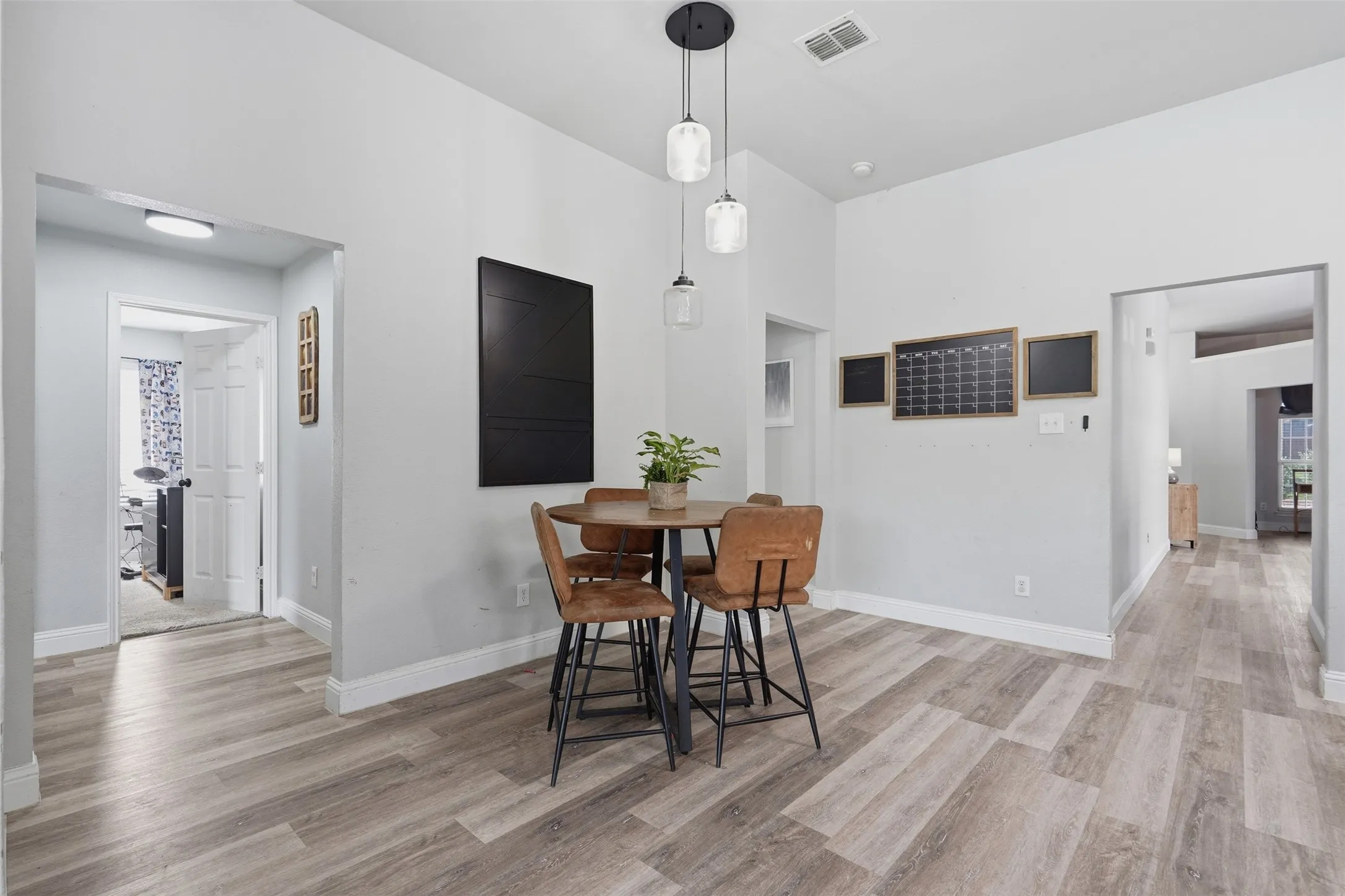 Spacious dining area featuring wood-finish flooring, light gray walls, and recessed lighting