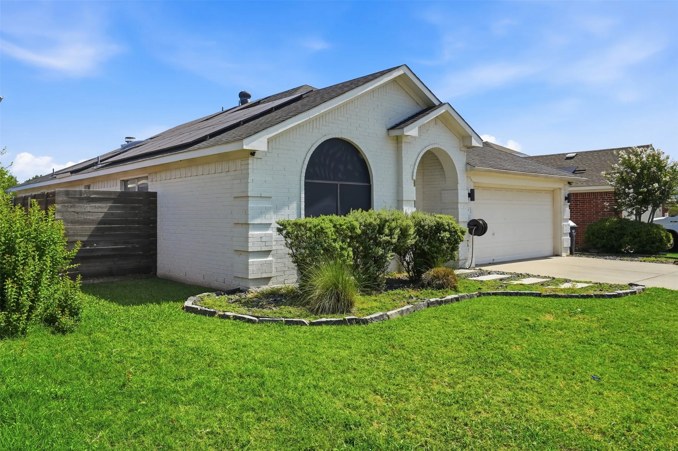 Single-story residence featuring a white brick exterior, a two-car garage, and a covered front entry