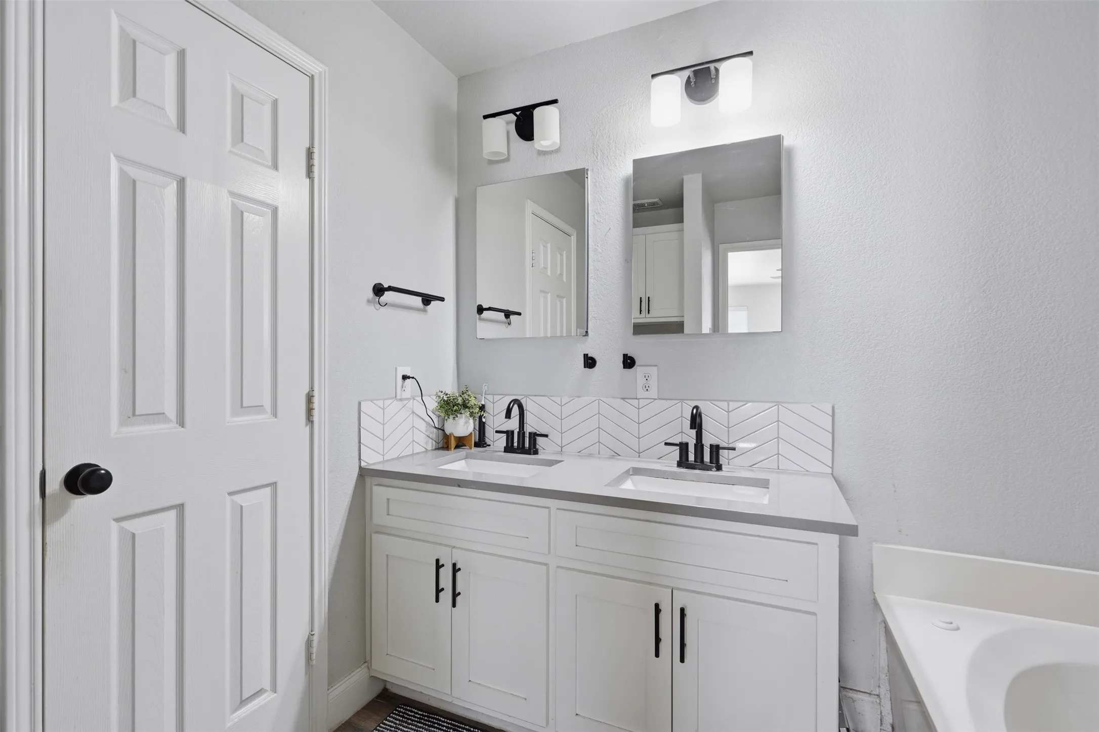 Dual vanity with white cabinetry, matte black hardware, and stone-look countertops