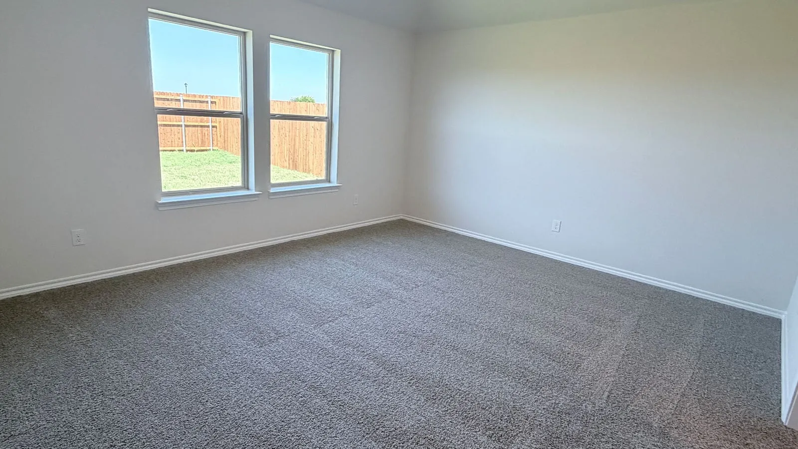 Bright secondary bedroom featuring new carpeting, dual windows with natural light, and clean white walls throughout