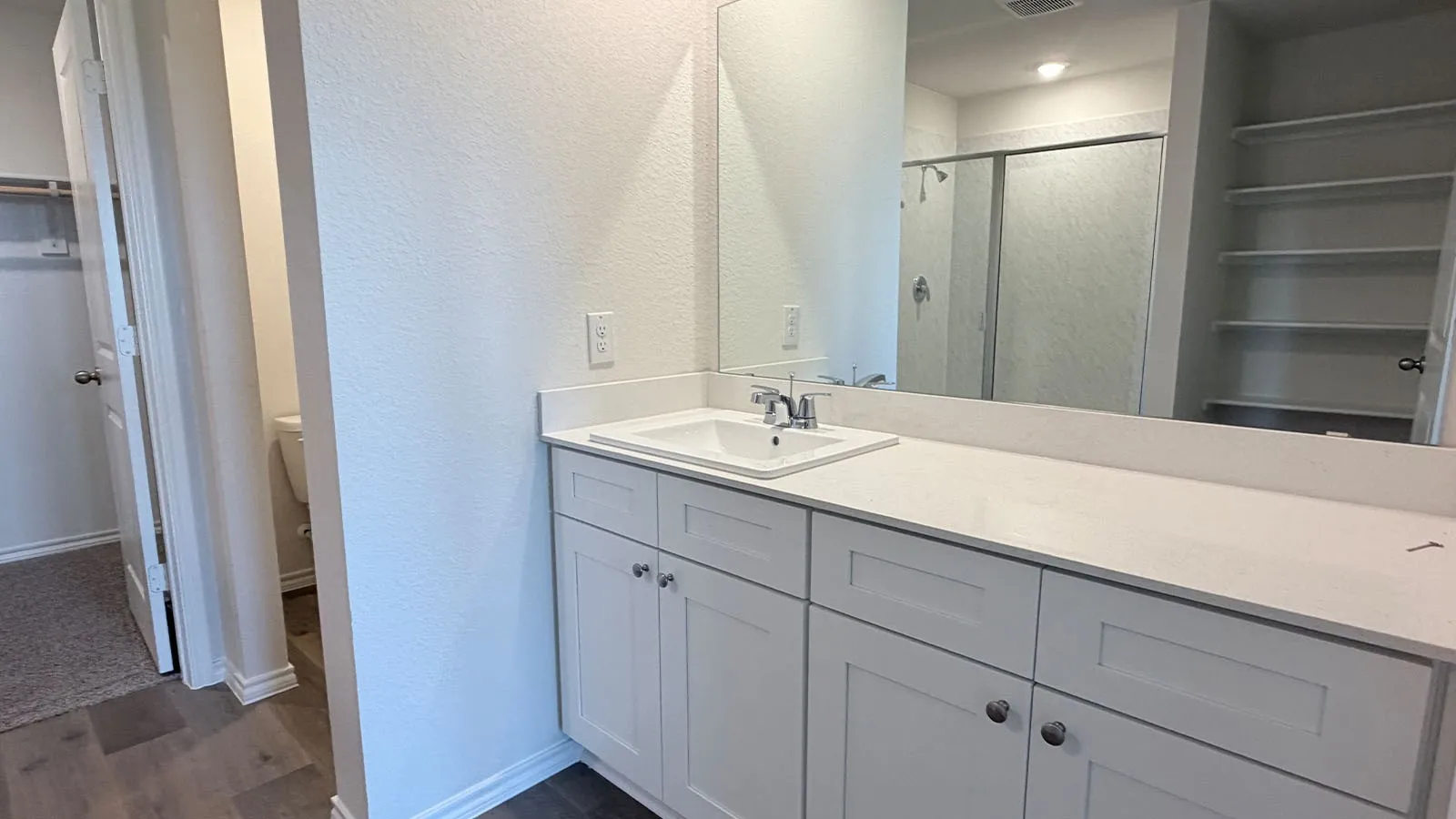 Spa-inspired primary bathroom featuring an extended double-vanity with white cabinetry, white quartz countertop, and chrome faucetry
