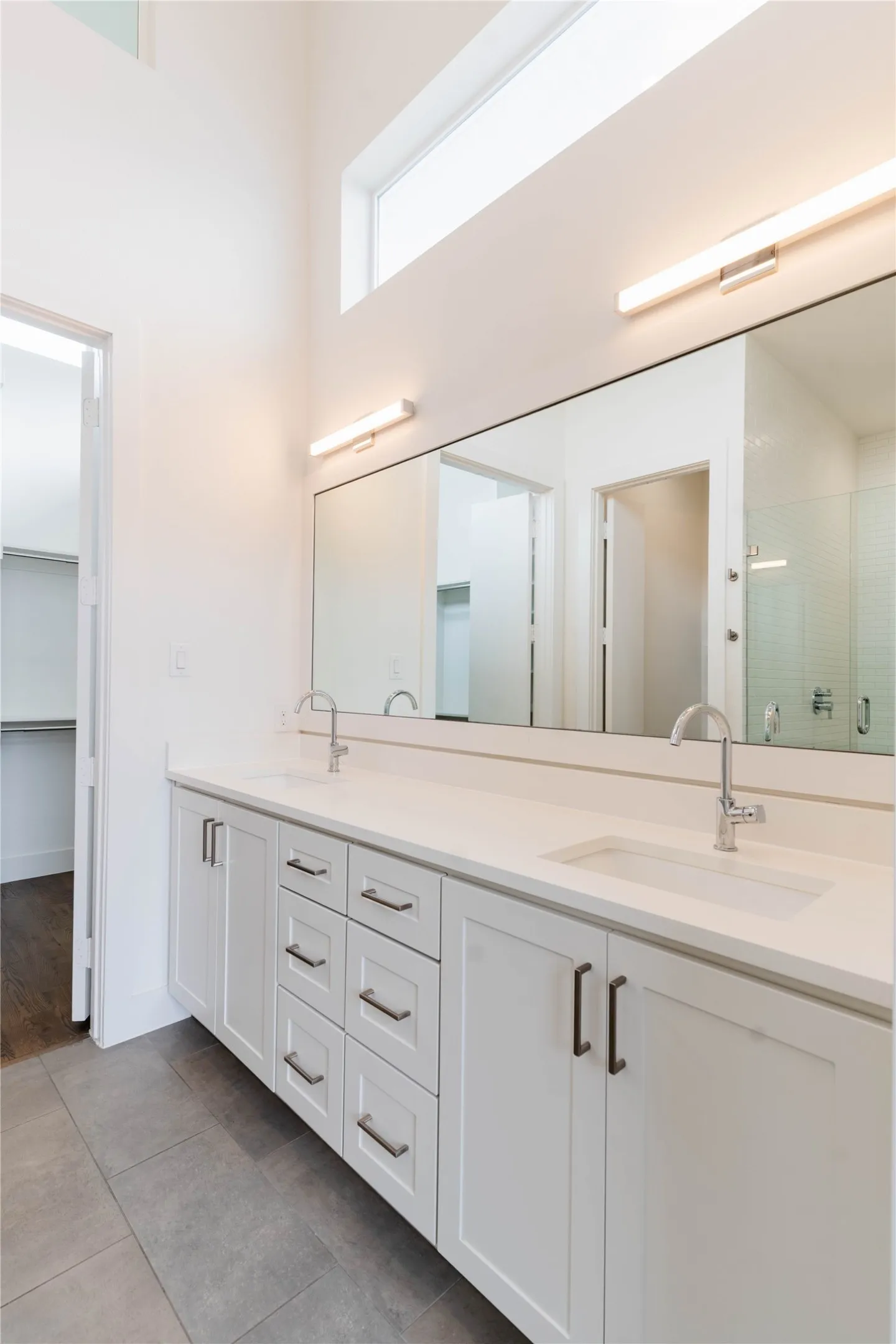 Double vanity with two integrated sinks, white cabinetry, and brushed nickel hardware